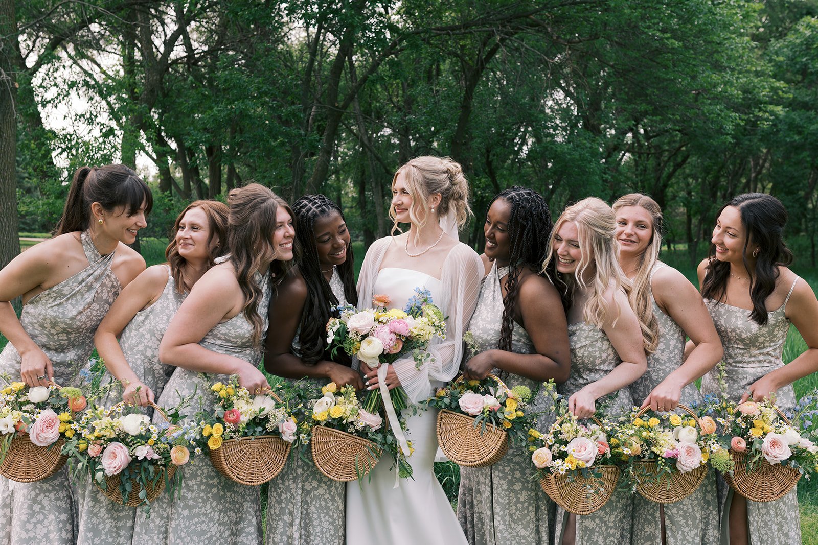 Wedding bride with bridesmaids holding flower baskets in a park.