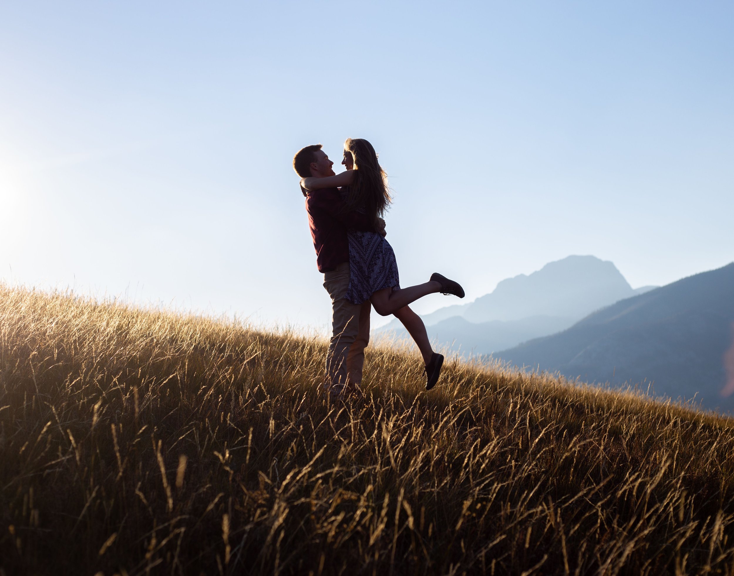 A man and woman embrace on a mountaintop in Jasper