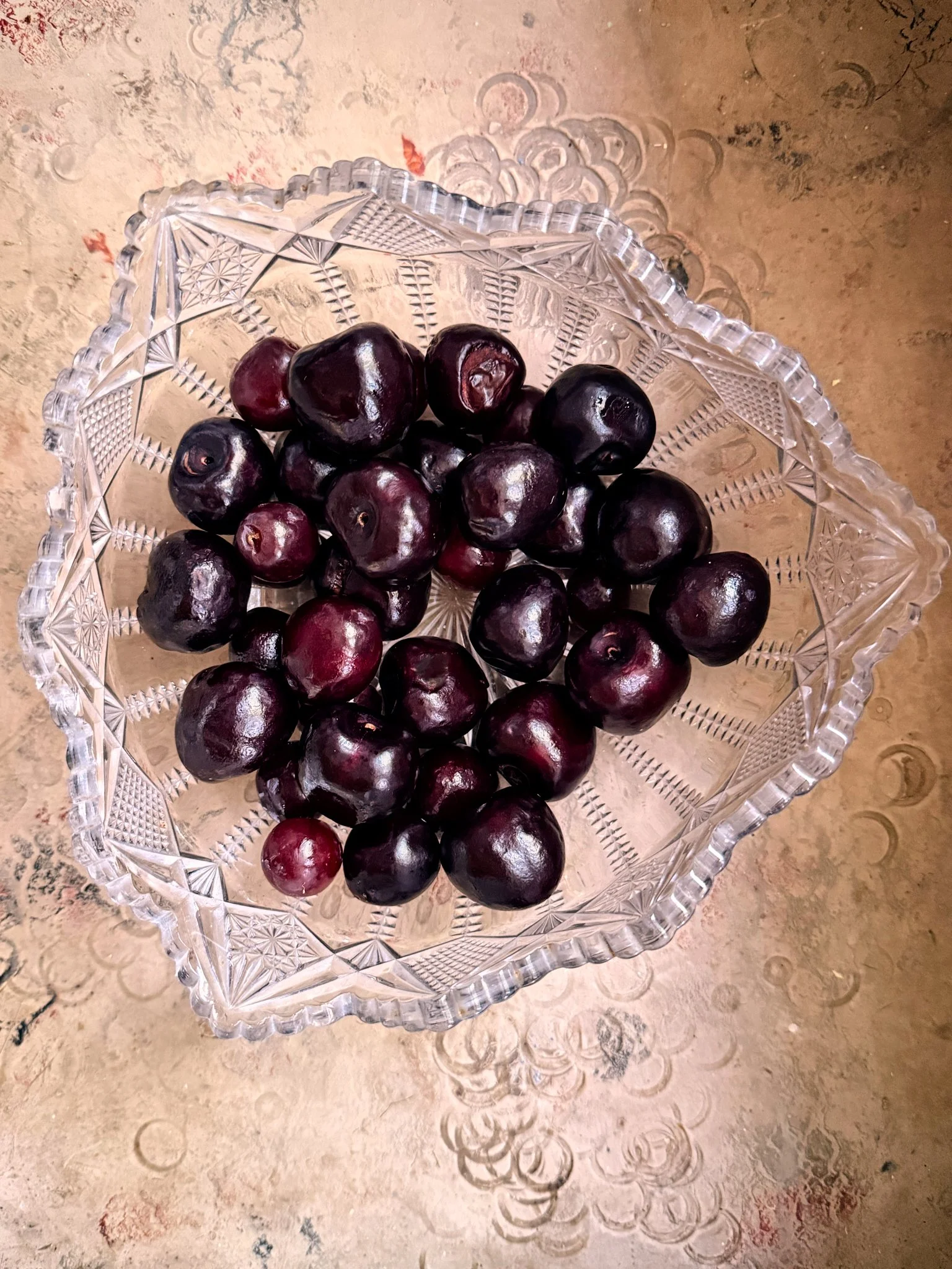 Black cherries in an ornate glass bowl.