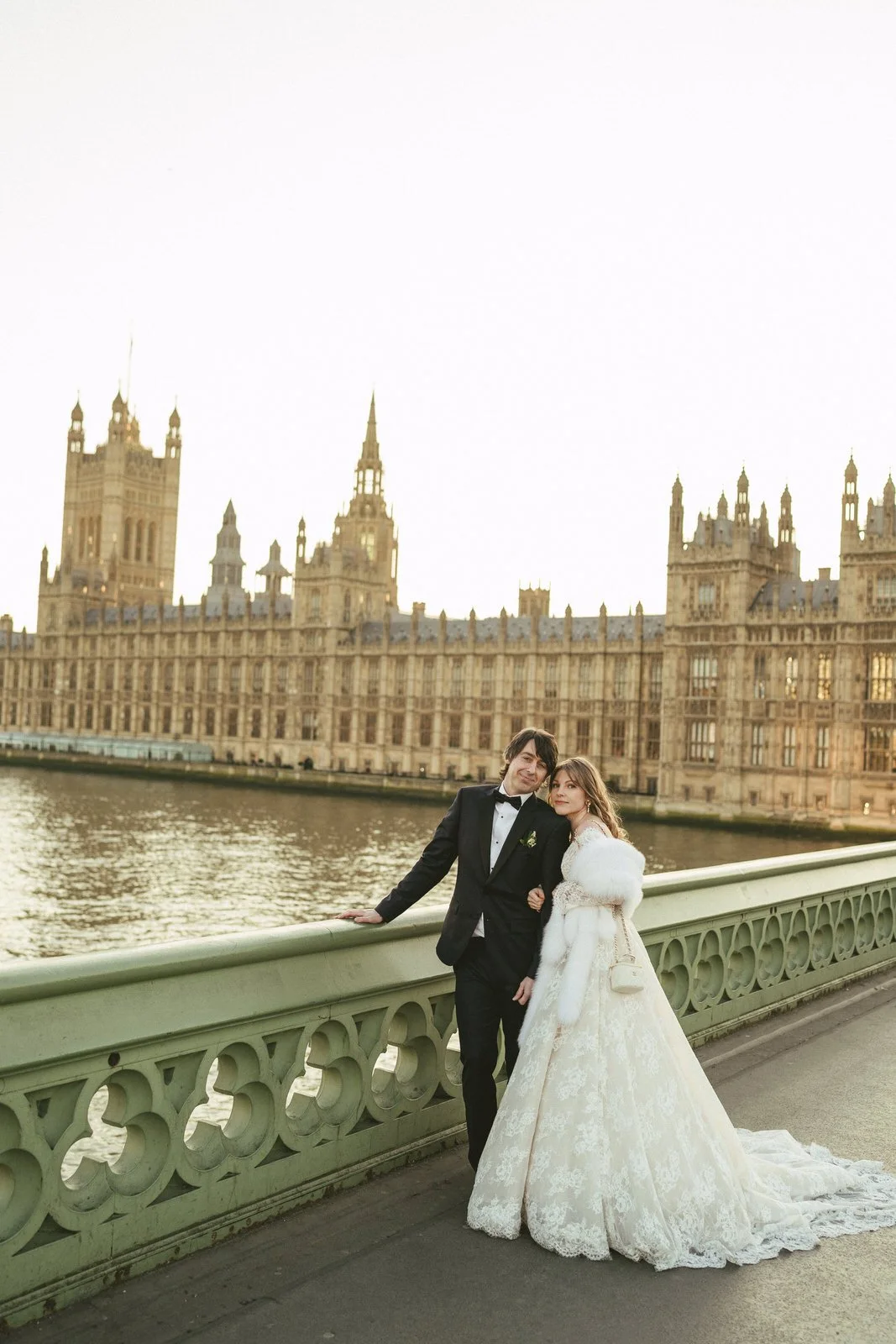 Couple in formal attire on Westminster Bridge with Houses of Parliament in background.