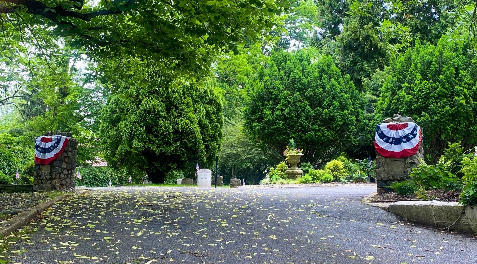 Cemetery entrance decorated with bunting and showing headstones.