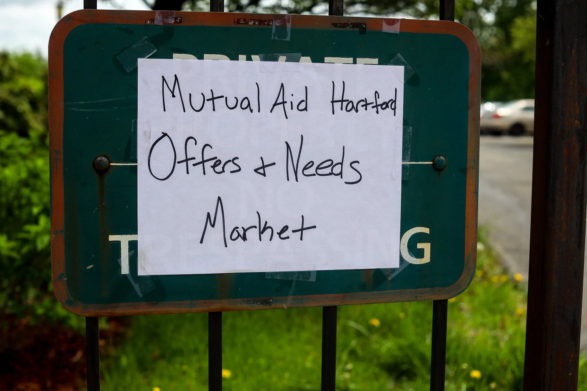 Handwritten sign on a white paper taped to a green metal sign, offering and requesting items for a mutual aid market in Hartford.