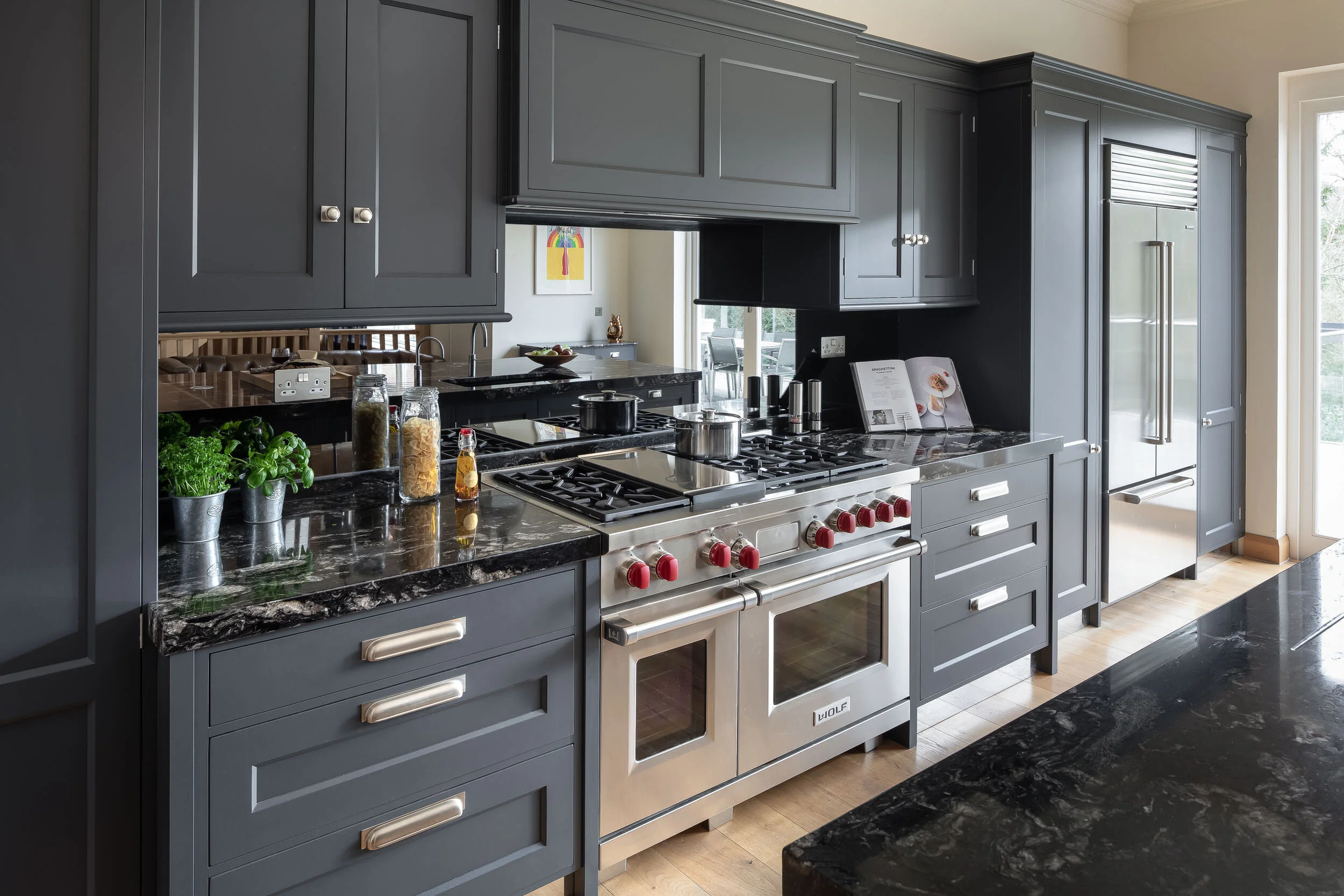 Modern kitchen with gray cabinets, stainless steel appliances, and marble countertops.