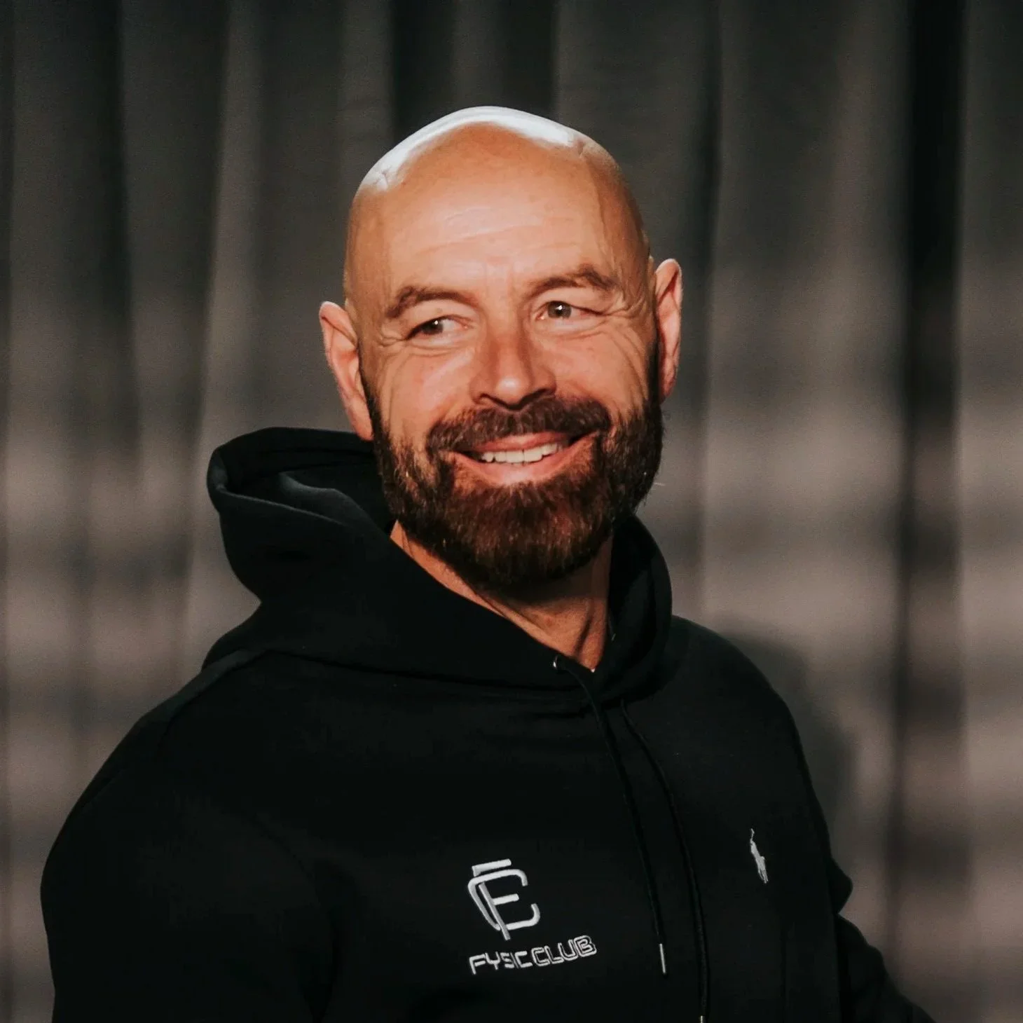 Peter van den Hurk, eigenaar van Fysic Club Den Bosch, met baard en glimlach in een zwarte hoodie met logo tegen een donkere achtergrond — profielfoto bij zijn review over Made by Anouk, Squarespace specialist van Nederland.