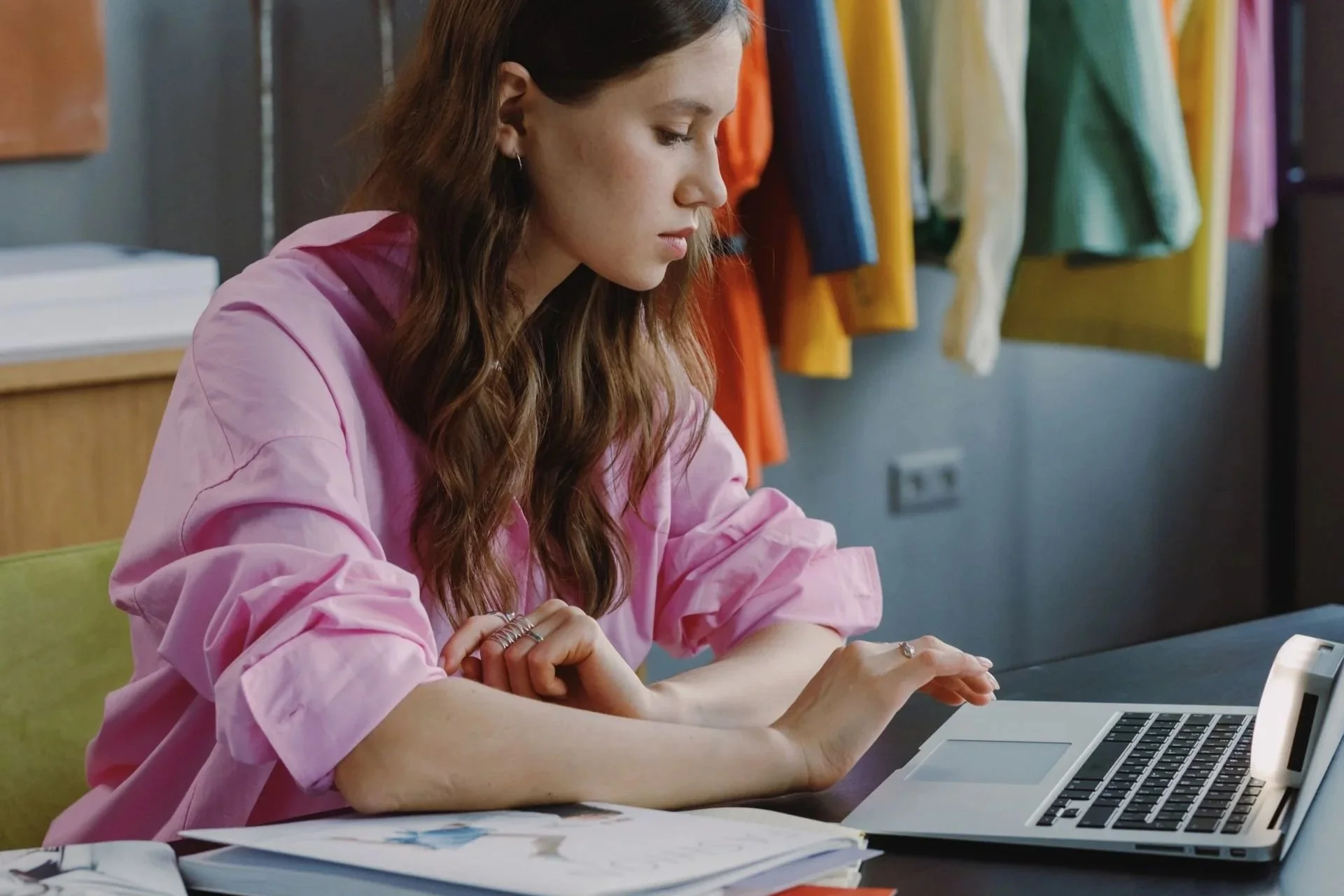 Nederlandse zzp-er in roze blouse werkt op haar laptop aan een website in een kleurrijke, creatieve werkplek