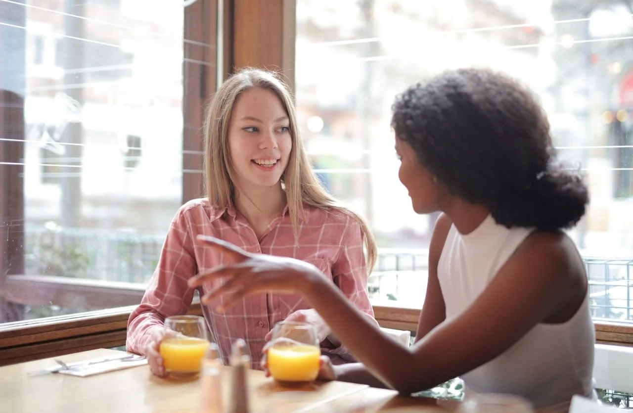 Twee vrouwen in gesprek aan tafel over de beste manier om hun Squarespace website te laten bouwen