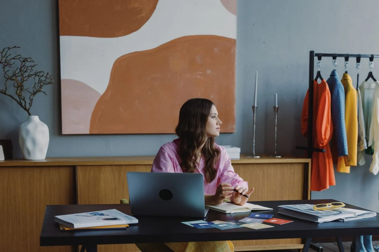 Business coach schrijft aantekeningen in een notitieboek naast haar laptop om het budget voor een Squarespace website te plannen