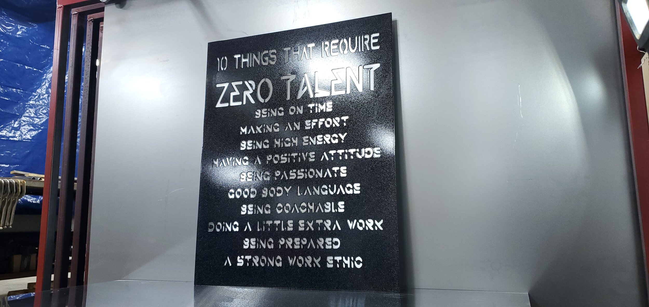 A black sign with motivational quote about qualities required for success, including being on time, making an effort, being high energy, having a positive attitude, being passionate, using good body language, being coachable, doing extra work, being