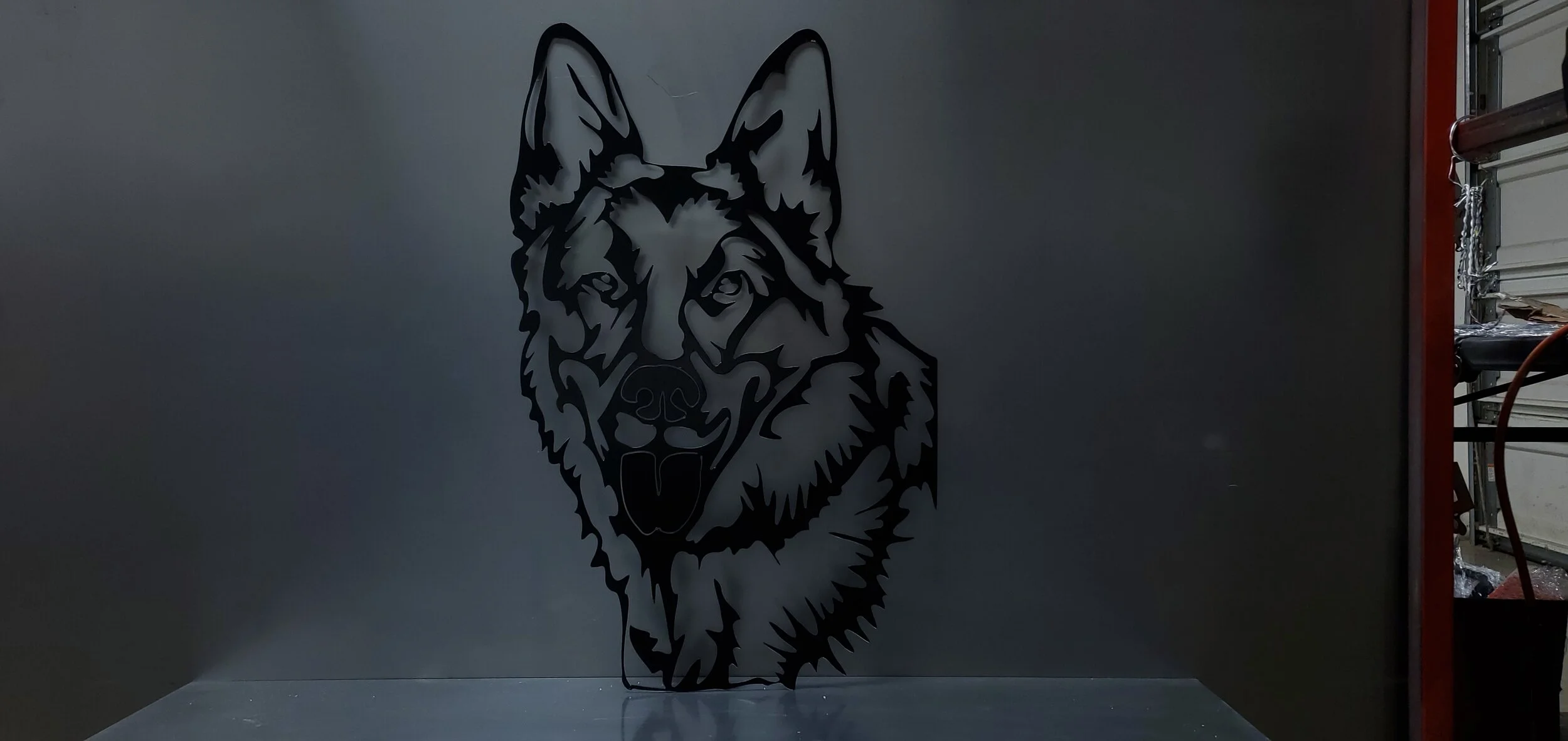 Black metal wall art of a wolf's head on a gray wall.