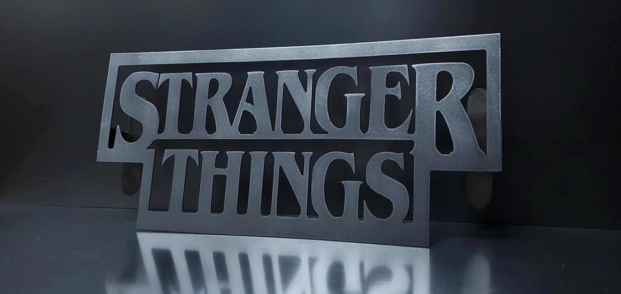 A black metal sign with cut-out text that reads 'Stranger Things'.