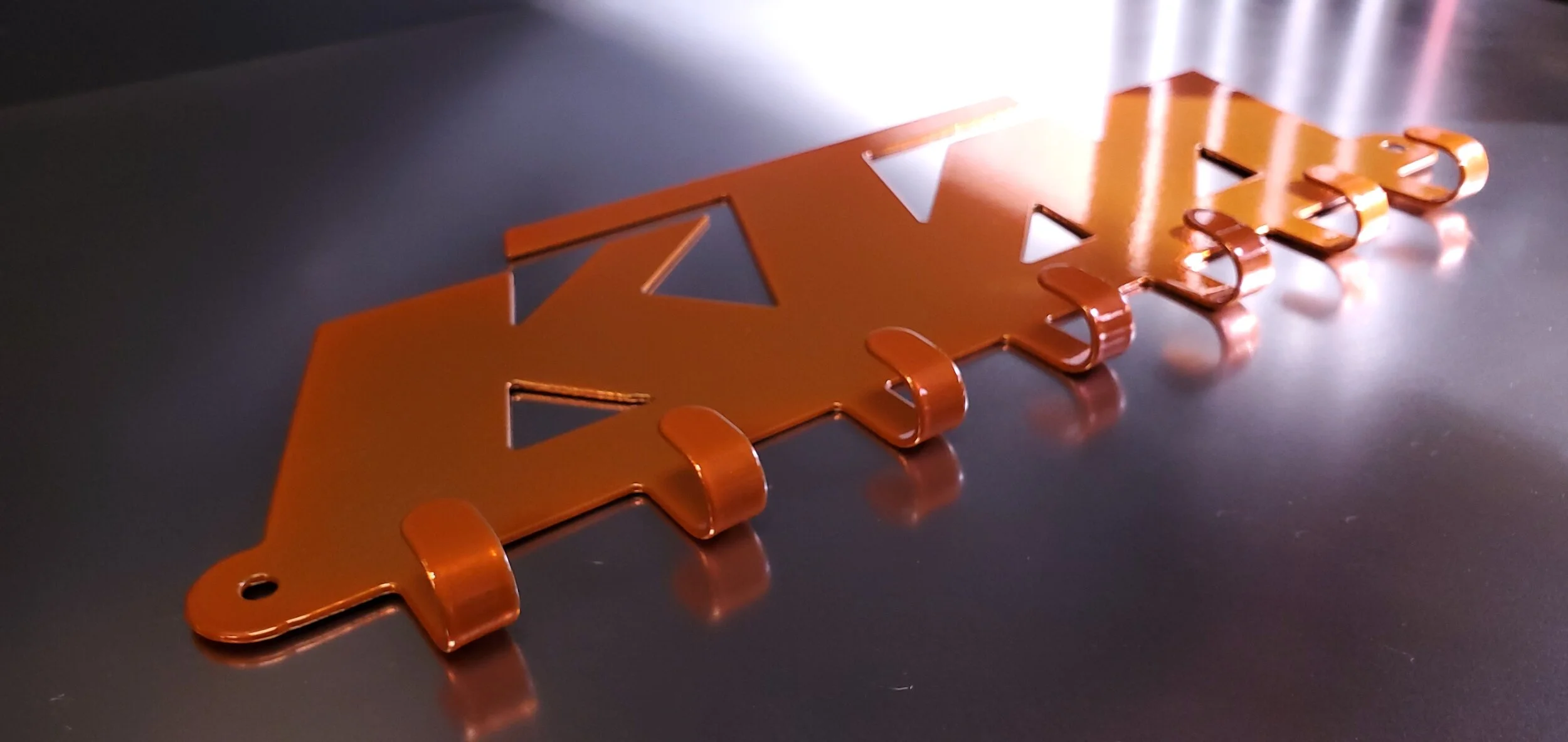 A copper-colored metallic sign that reads 'WATER' with a lightning bolt symbol, placed on a reflective black surface.