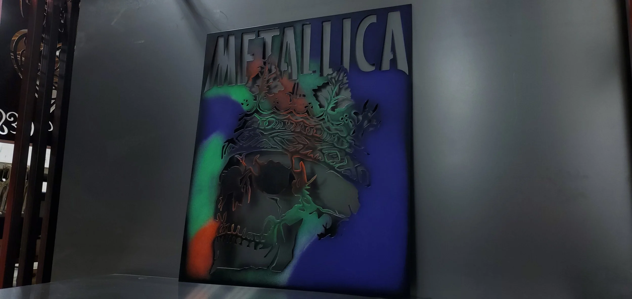 Metallica logo cut-out wall art with multicolored lighting effects.