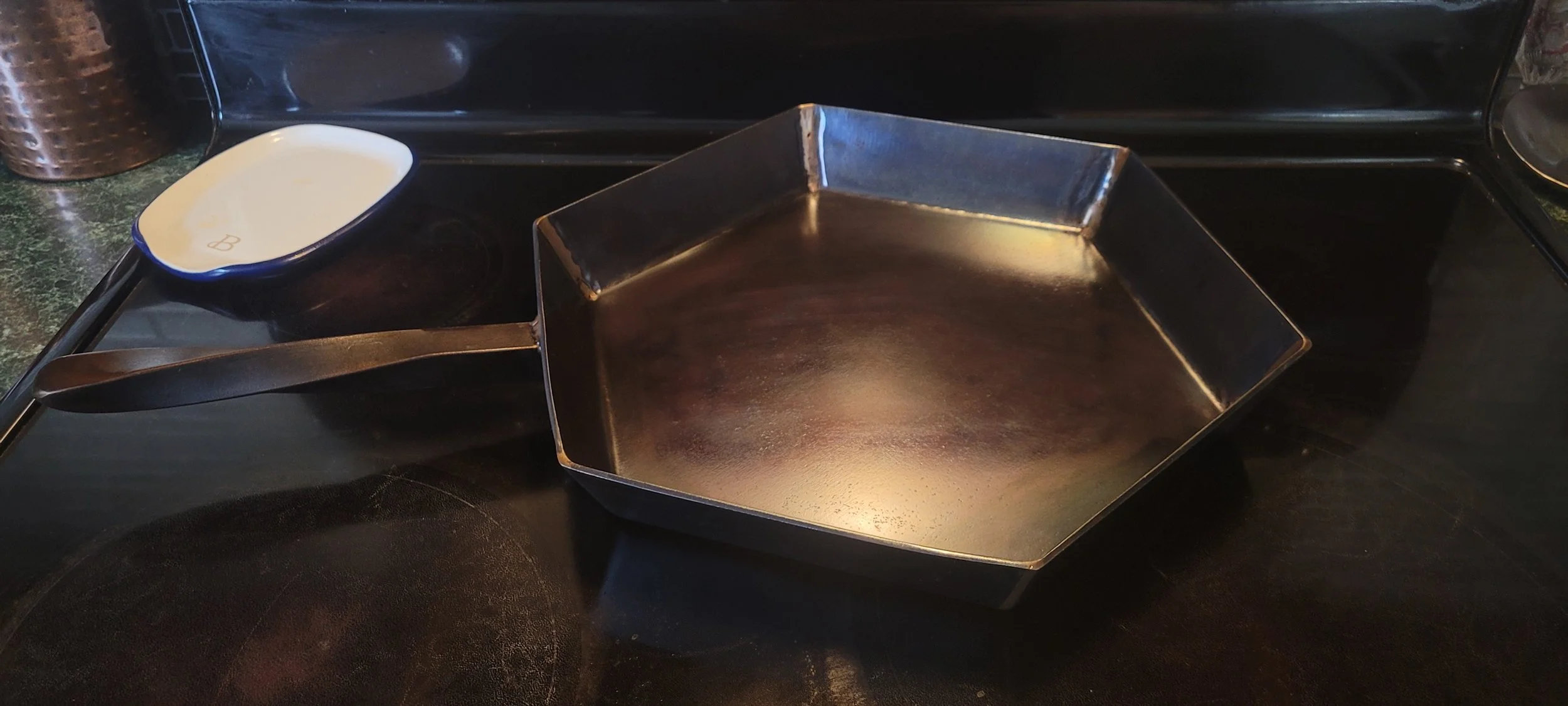 Empty square metal griddle and a small white dish on a black stovetop. Made by Turn 2 Csutomz