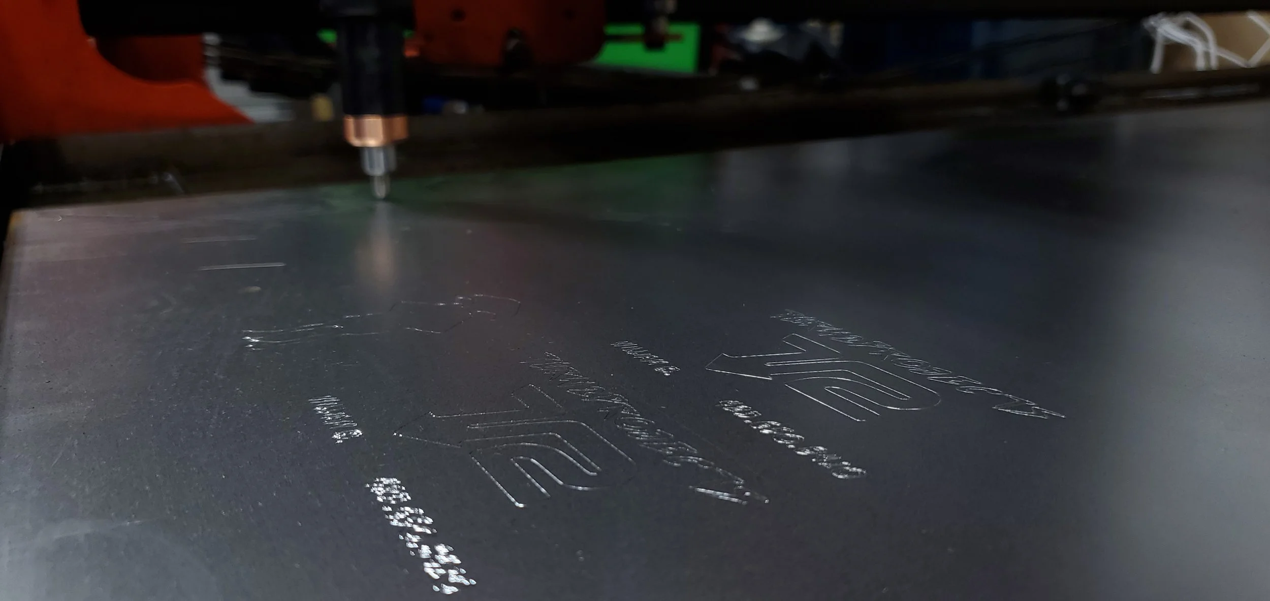 Close-up of a laser engraving machine etching text onto a metallic surface.