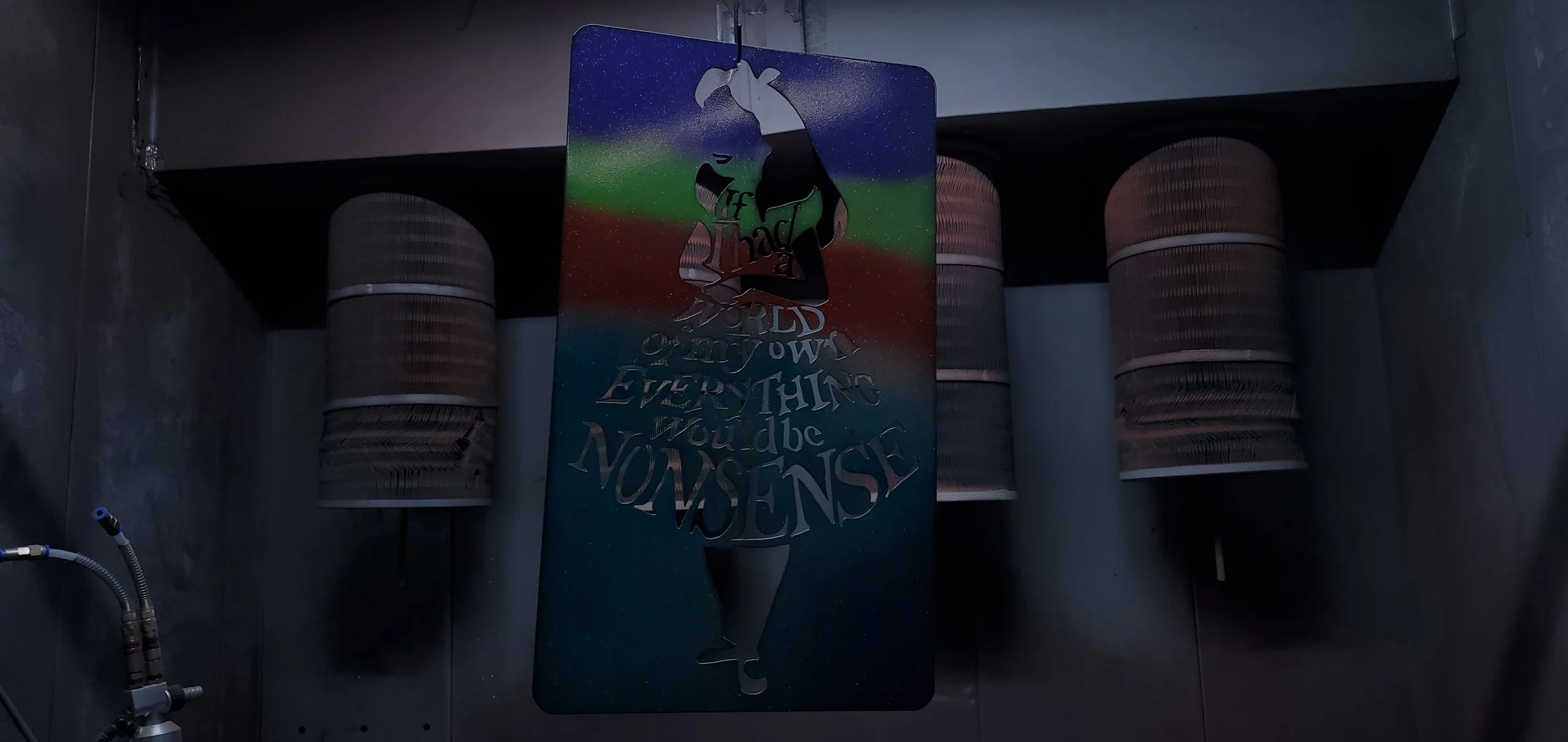 Metal sign with a cutout of a woman swinging on a rope, surrounded by colorful sky background; the sign has the quote, 'If I had to choose between loving you and breathing, I would use my last breath to say I love you.' The sign is hanging inside an 