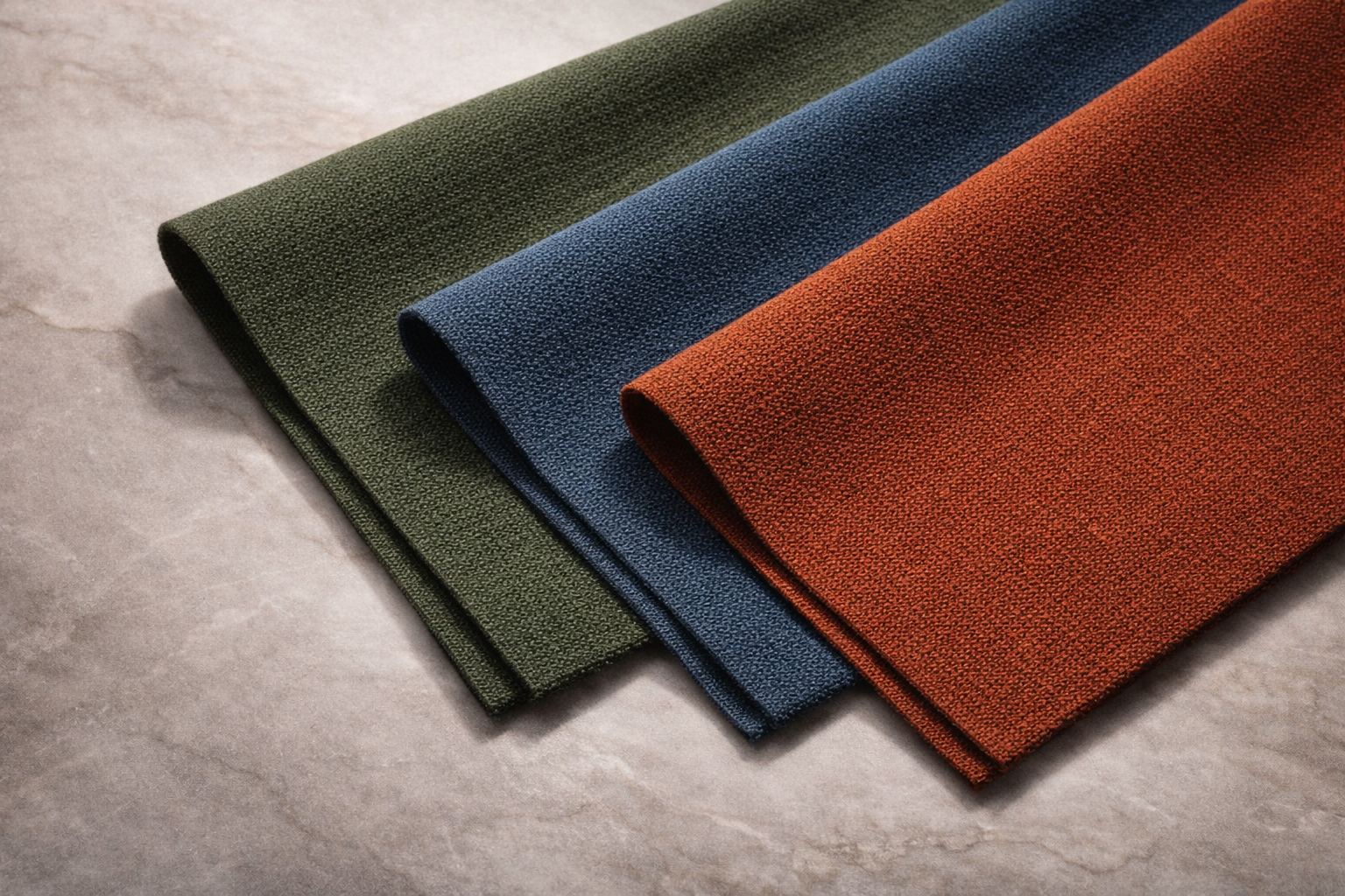 Camira X2 fabric samples in dark green, blue and rust orange.