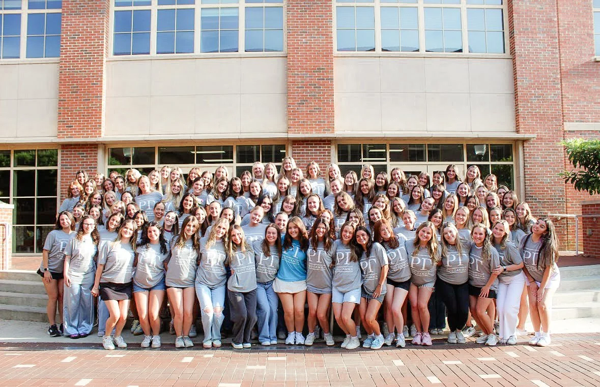 Group of women posing for a photo in front of a brick building