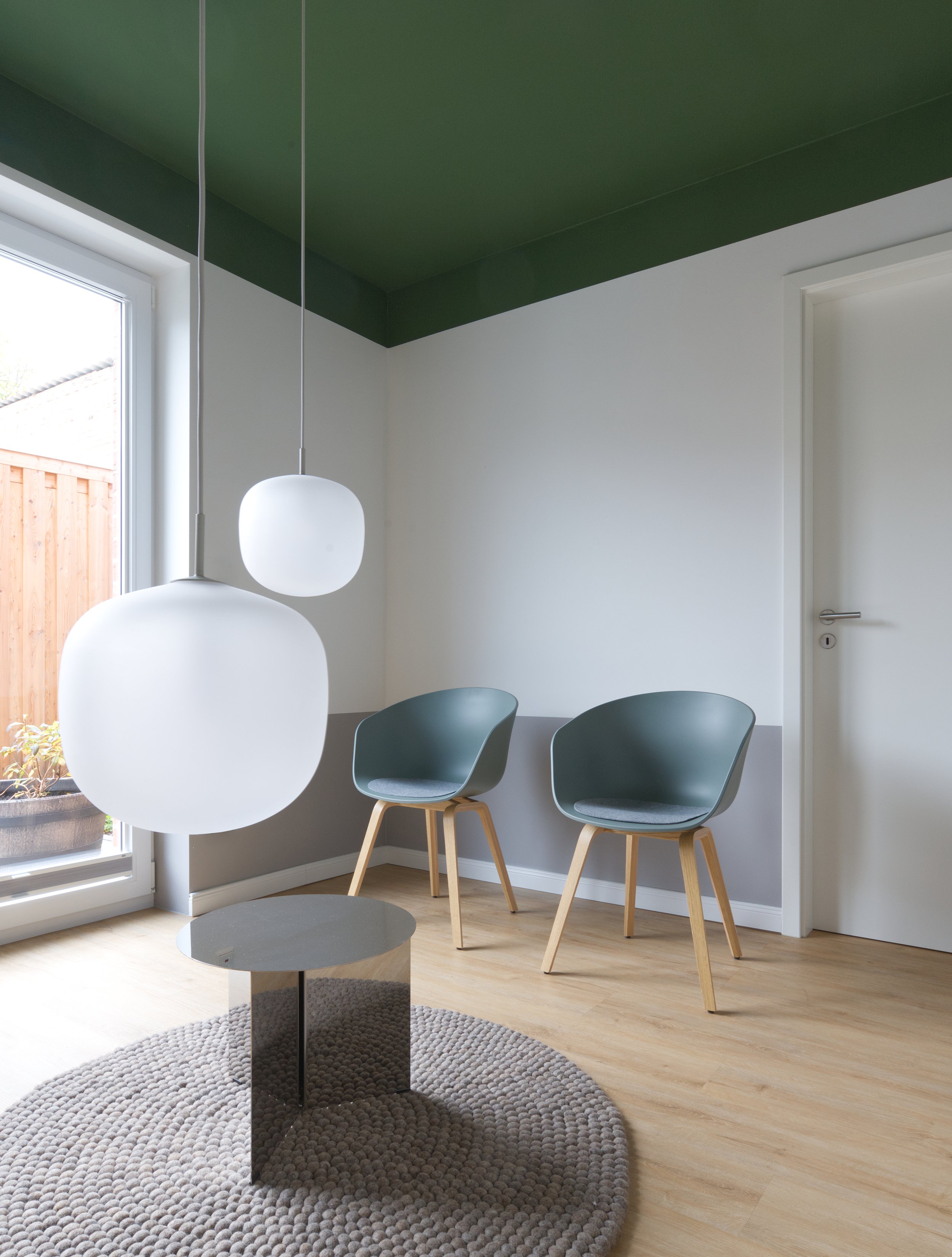 Wartezimmer mit grüner Decke, Holzboden und niedrig hängenden Pendelleuchten; Interior Design