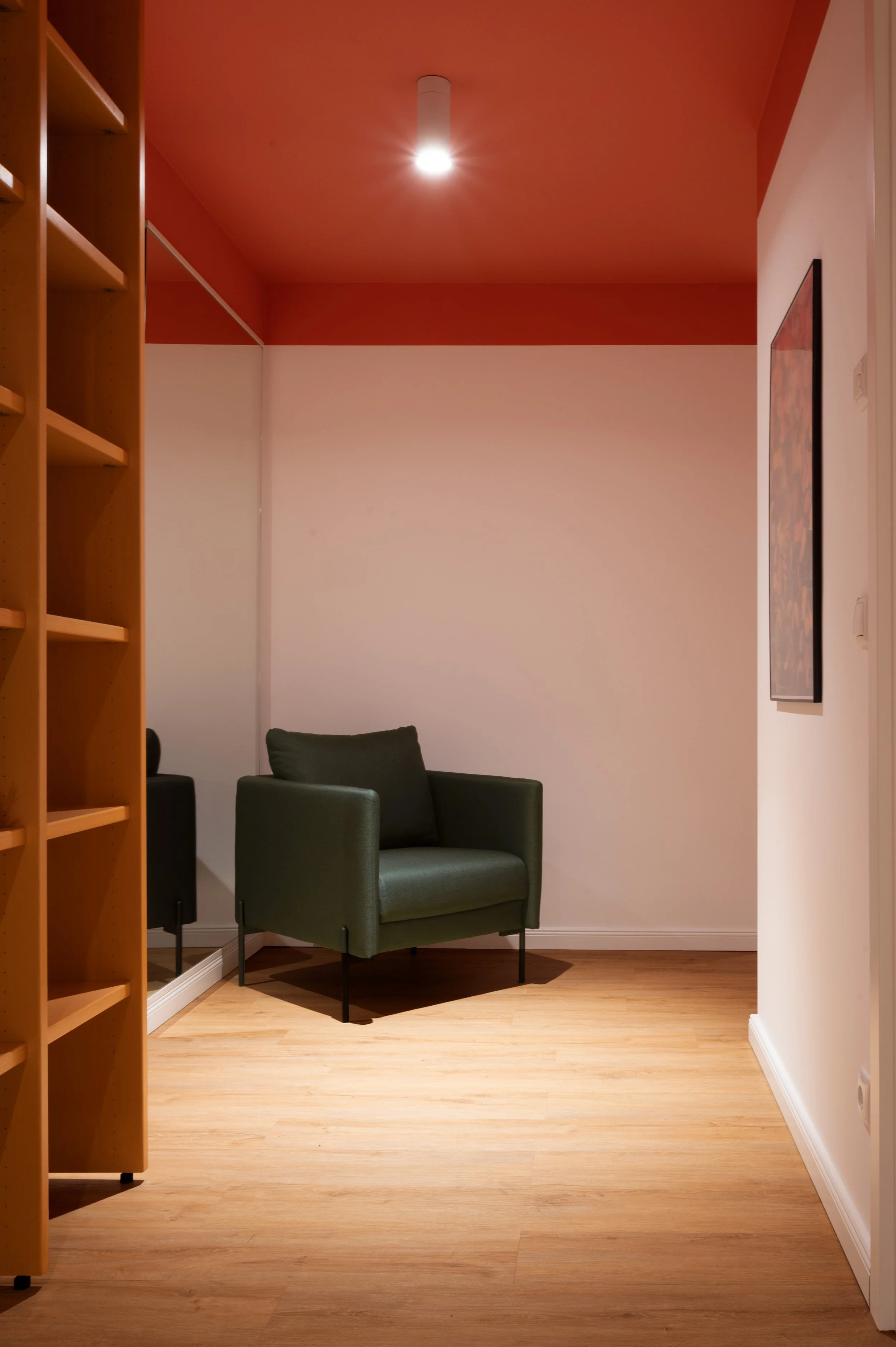 Flur mit Holzboden und roter Deckenfarbe und grünem Lounge-Sessel