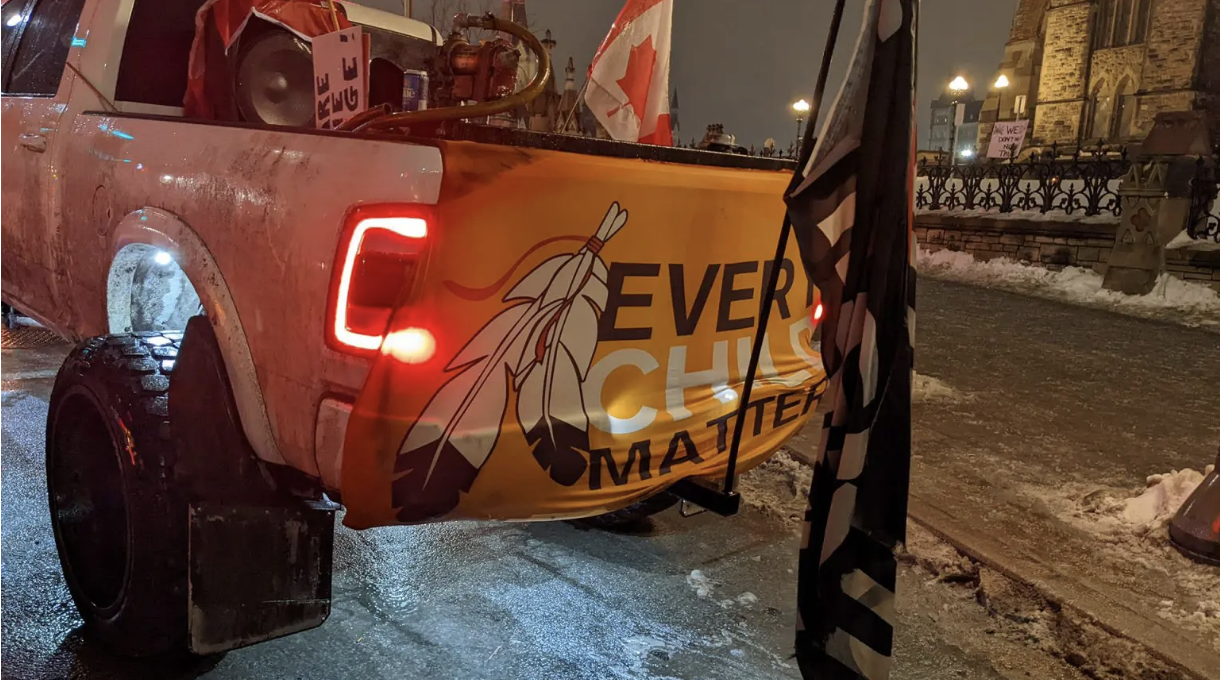 Figure 1.2: Pickup truck at the protest with an ‘Every Child Matters Flag hung across its tailgate&nbsp;
