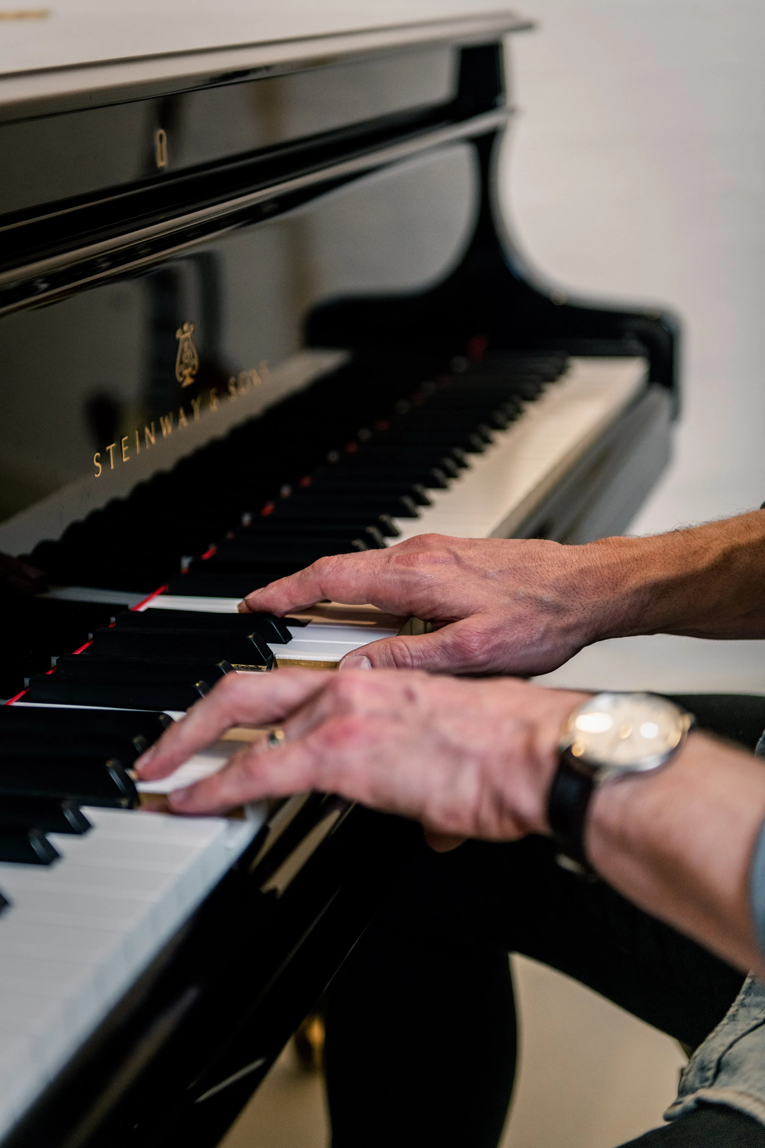 Close-up of hands playing grand piano during vocal coaching session