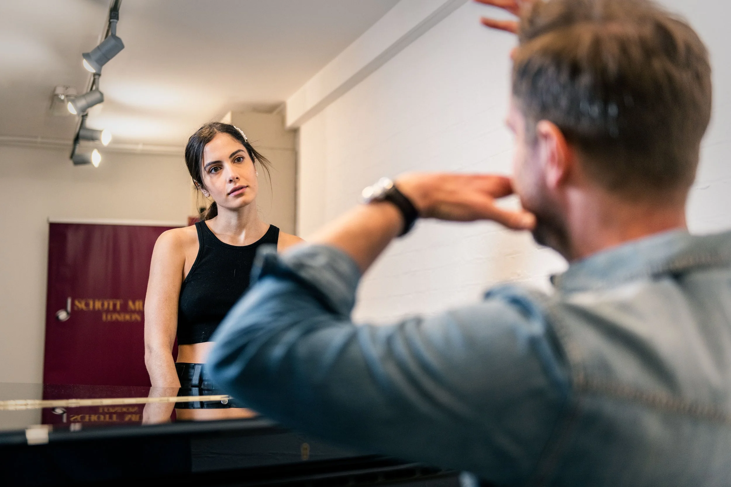 Vocal coaching session with teacher demonstrating vocal technique to singer
