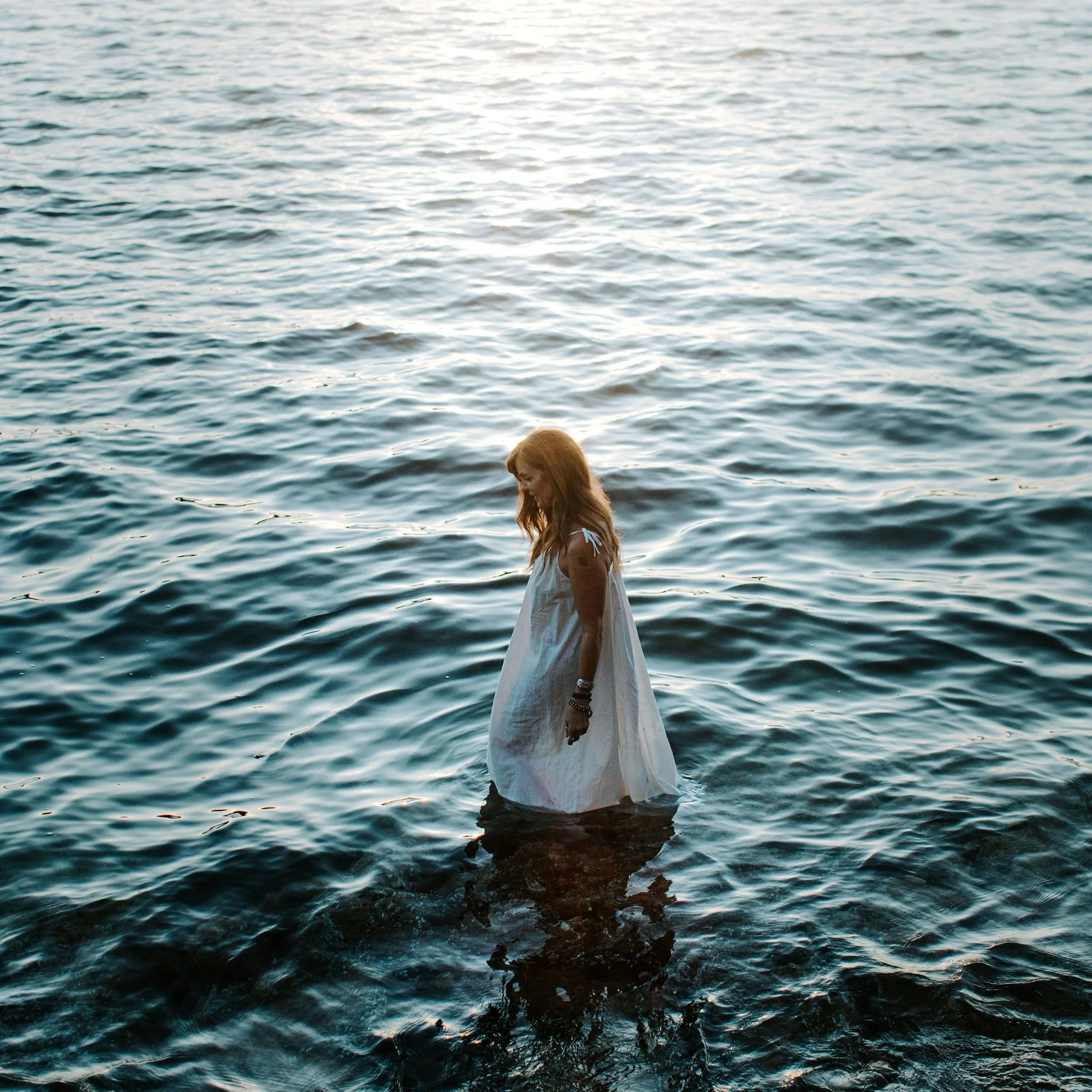 Angela Prider, shamanic practitioner  standing in ocean dark blue. Dream Interpretation Readings