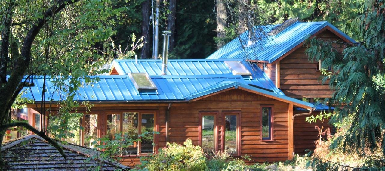 Main wooden lodge with aqua roof in woods at spiritual retreat centre, animism, shamanism