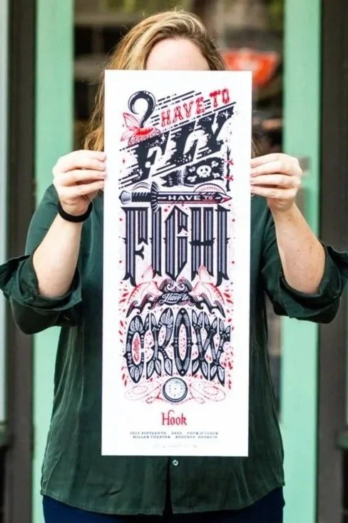 Rachel holds up a hand-lettered and illustrated poster design for the movie Hook