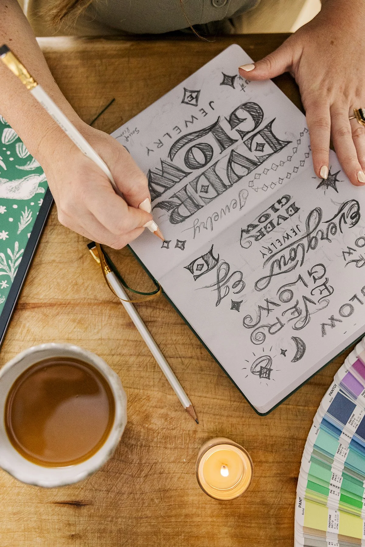 Rachel sketches concepts for Everglow Jewelry logo in her notebook