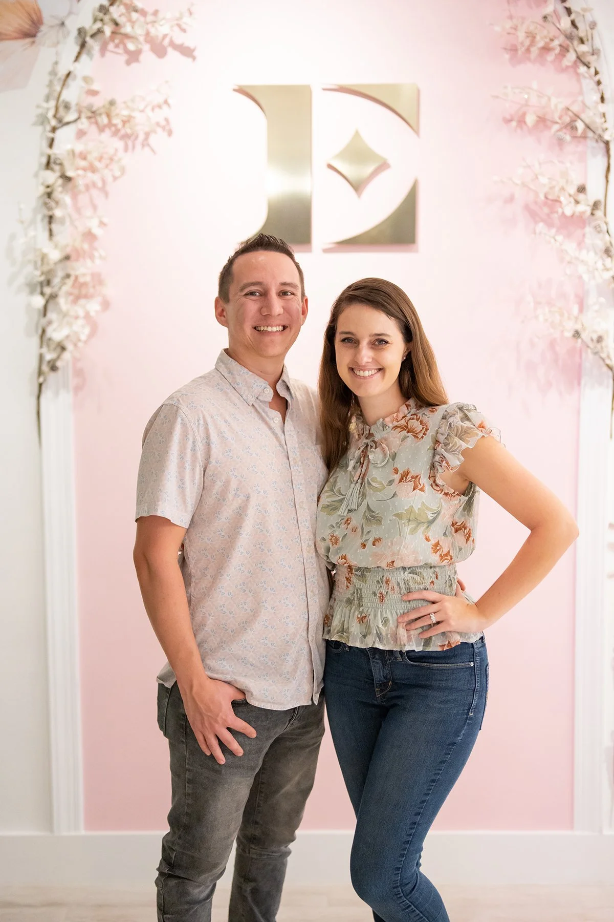 Everglow Jewelry owners pose inside their store facing camera and smiling with Everglow Jewelry signage in the background