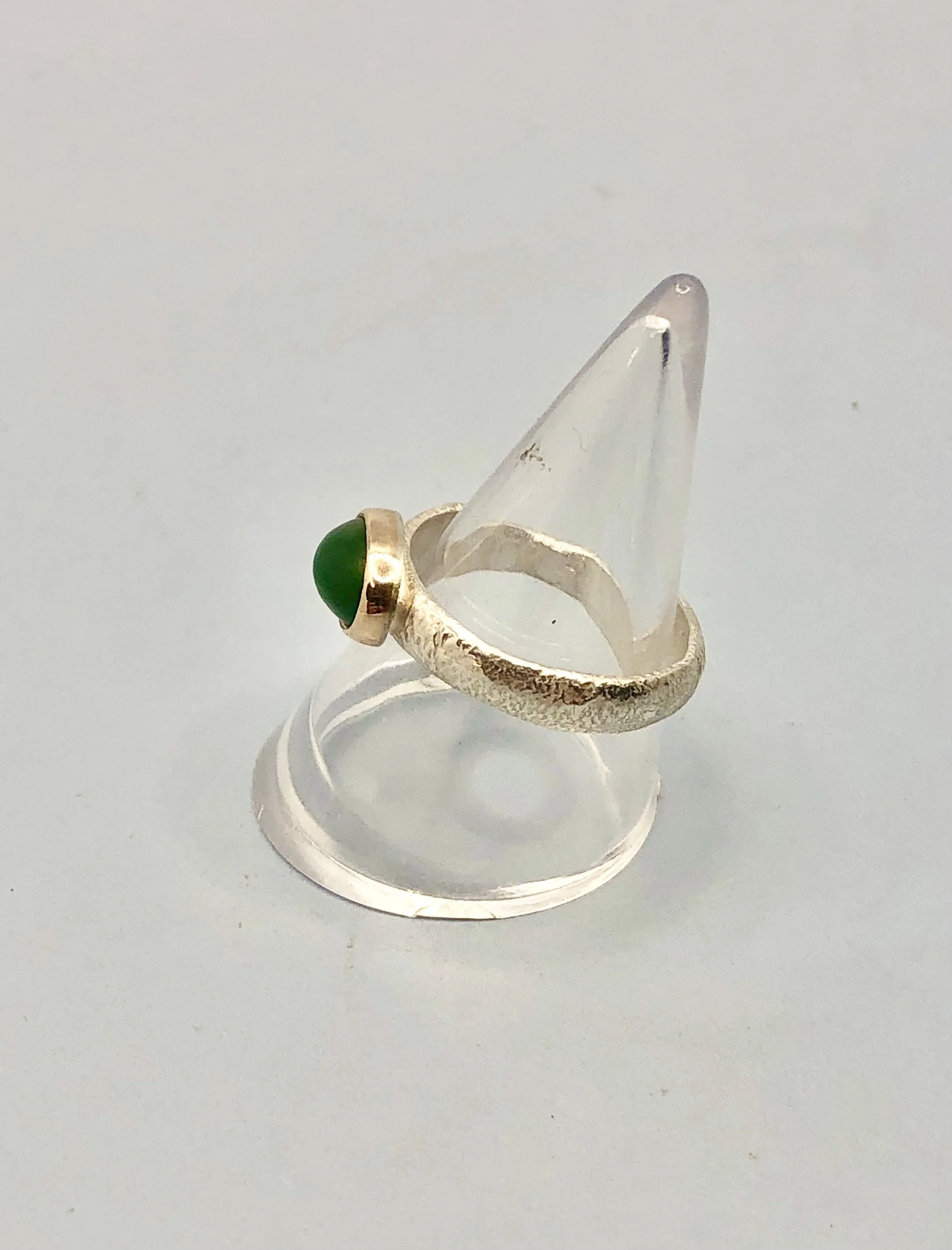 Side profile of pounamu oval gold ring showing textured sterling silver band