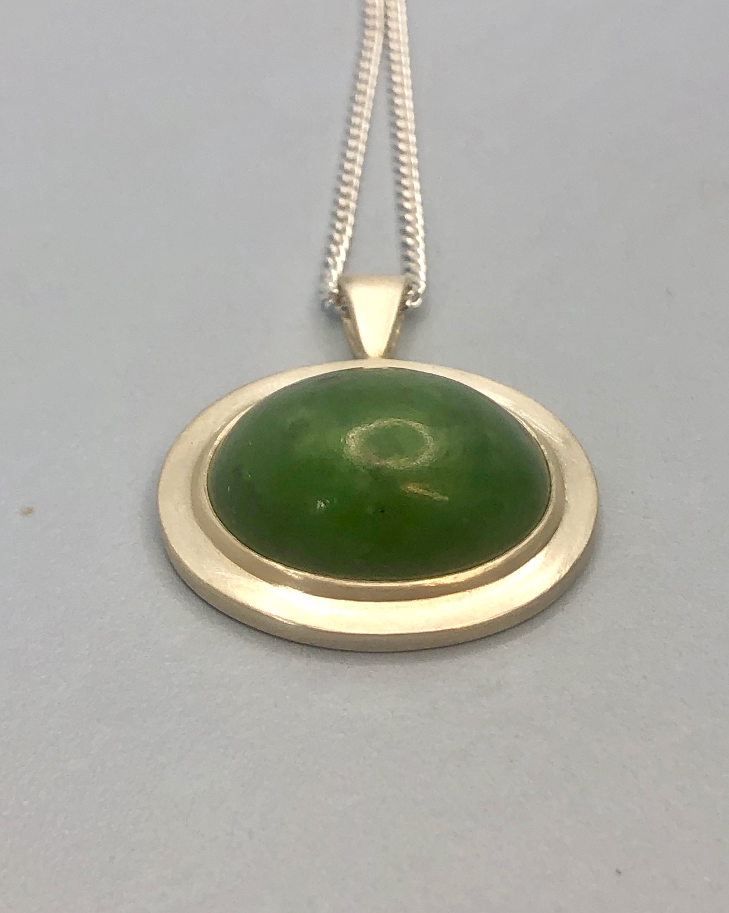 NZ greenstone pendant lying down from low angle to show height.