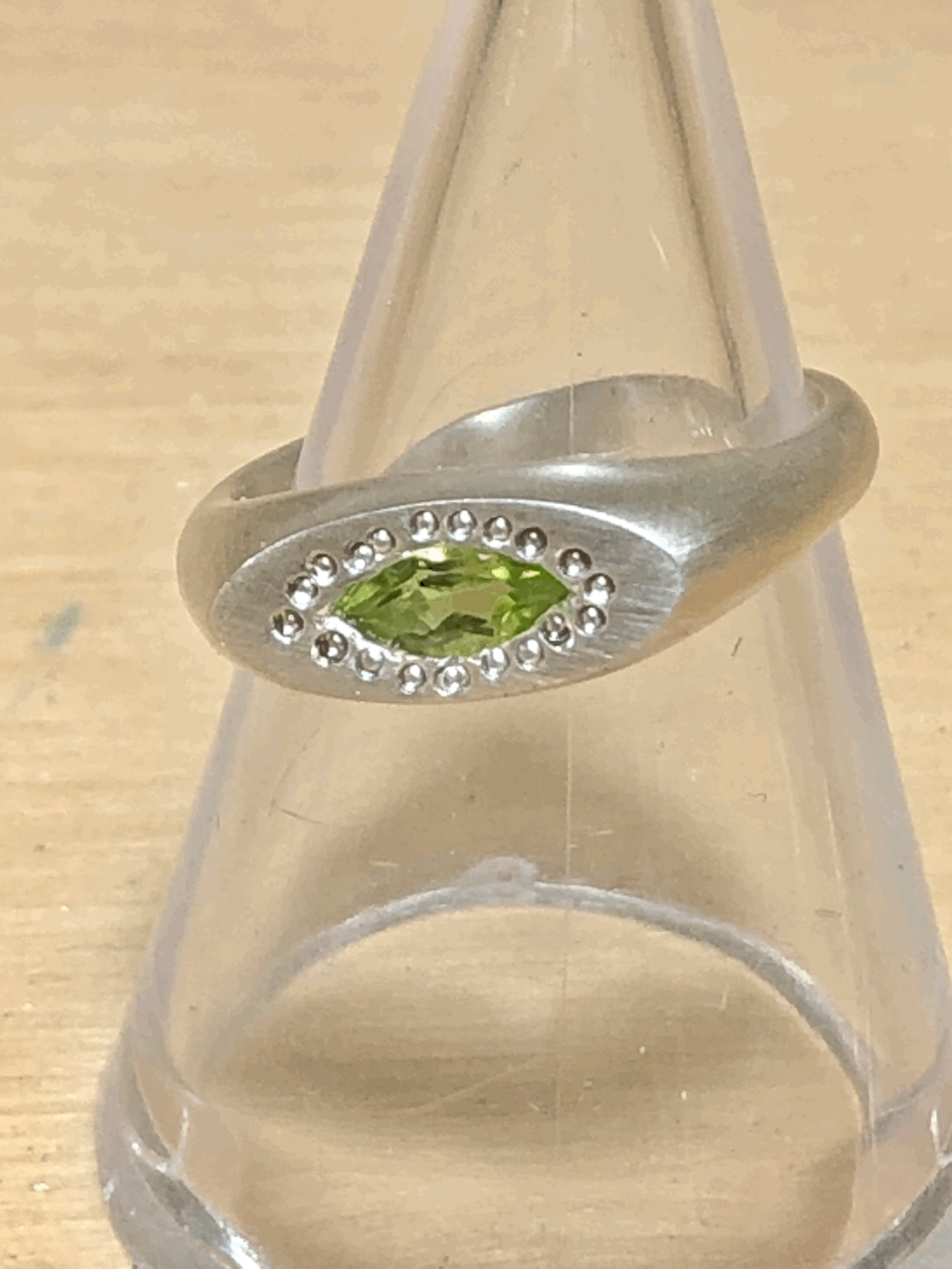 Close-up of marquise peridot gemstone set into handcrafted sterling silver signet ring