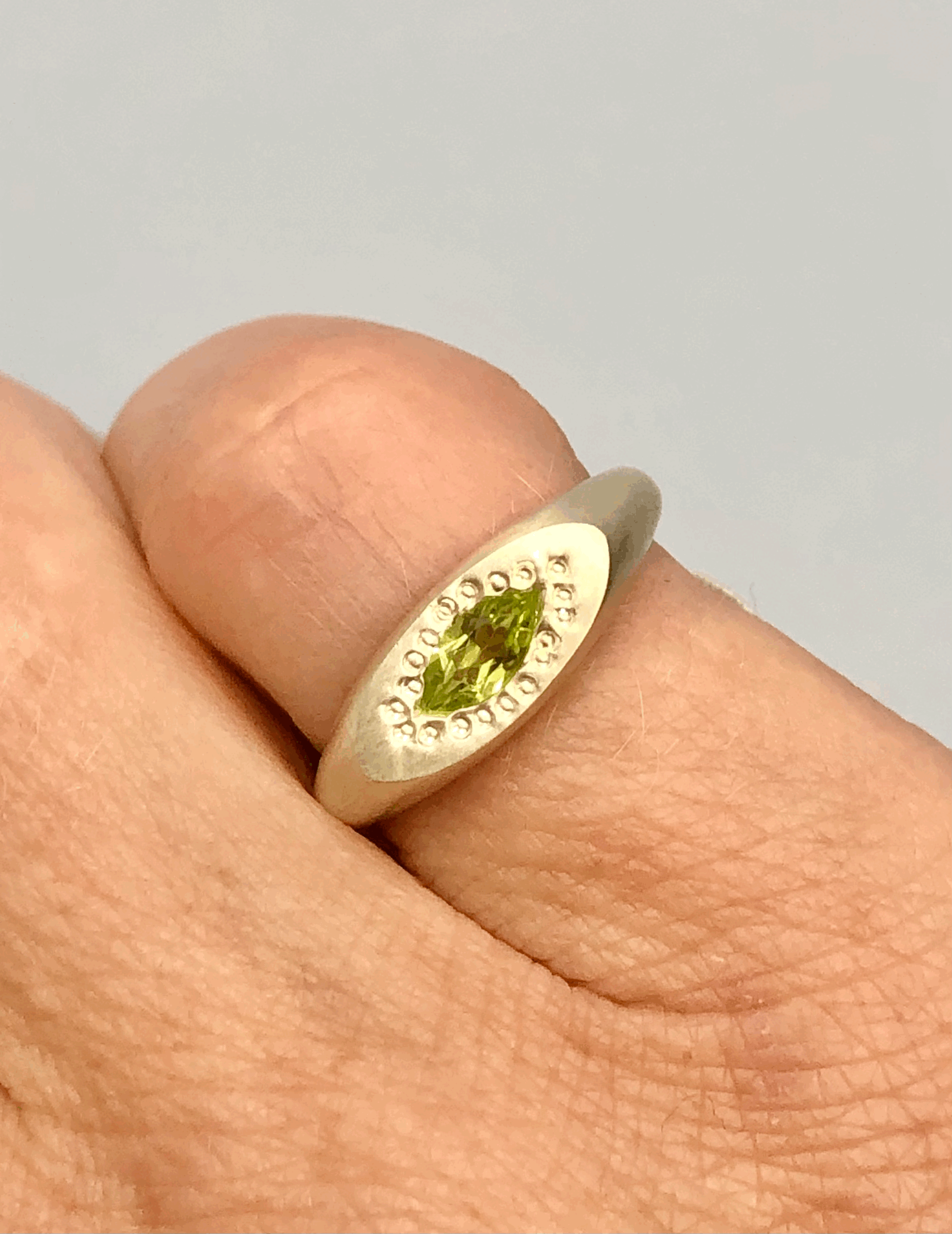 Marquise peridot silver signet ring worn on pinky finger showing scale and fit