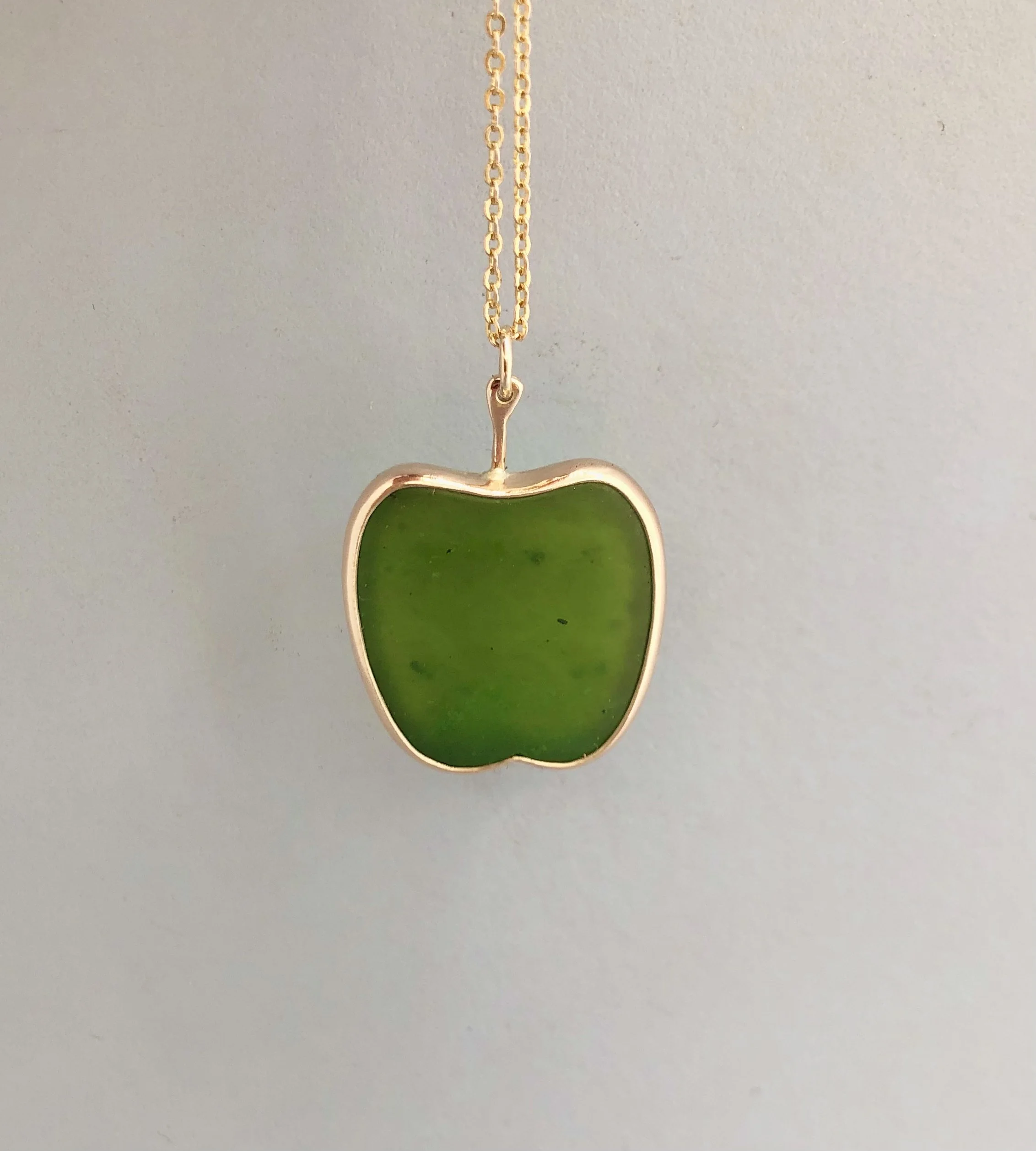 9k gold & pounamu apple pendant shown hanging, front view.