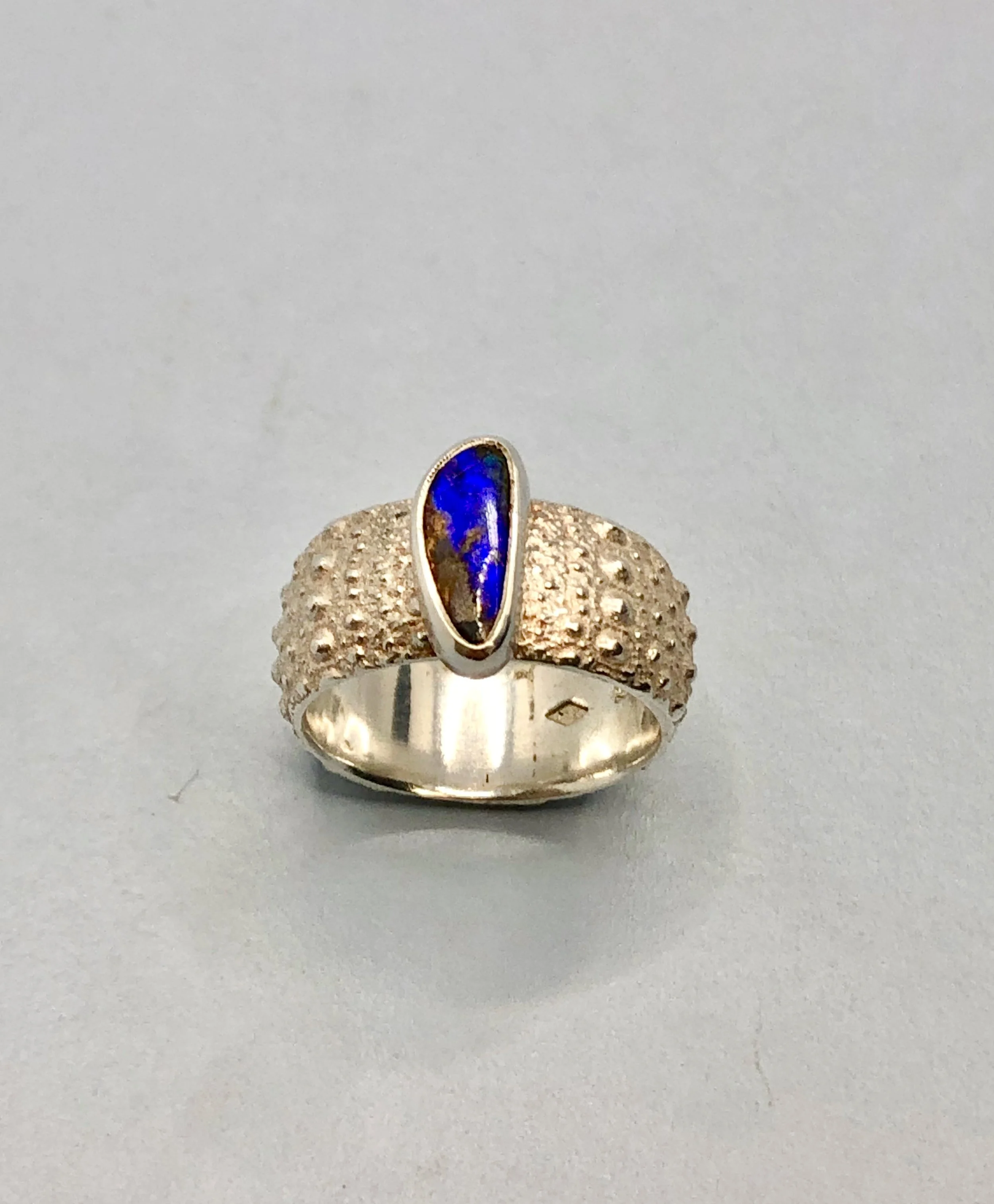 Top angled view of Australian boulder opal ring set in sterling silver on a 925 Kina textured ring.