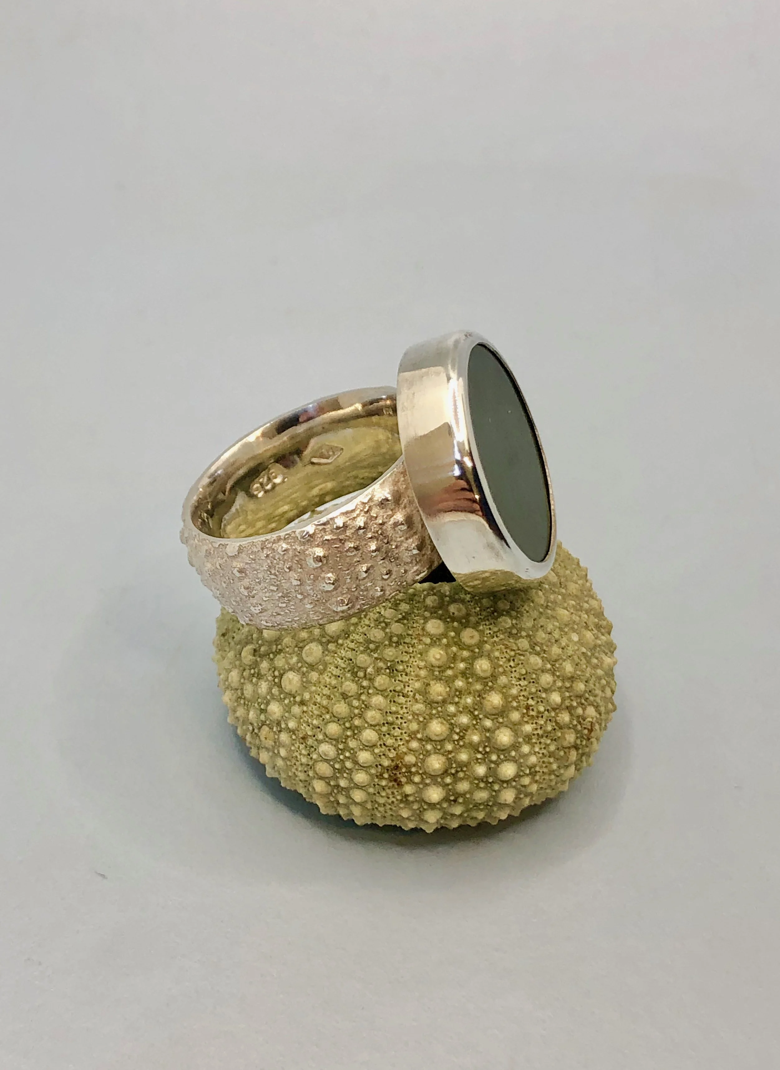 Side view of Kina and pounamu disc ring sitting on a sea urchin