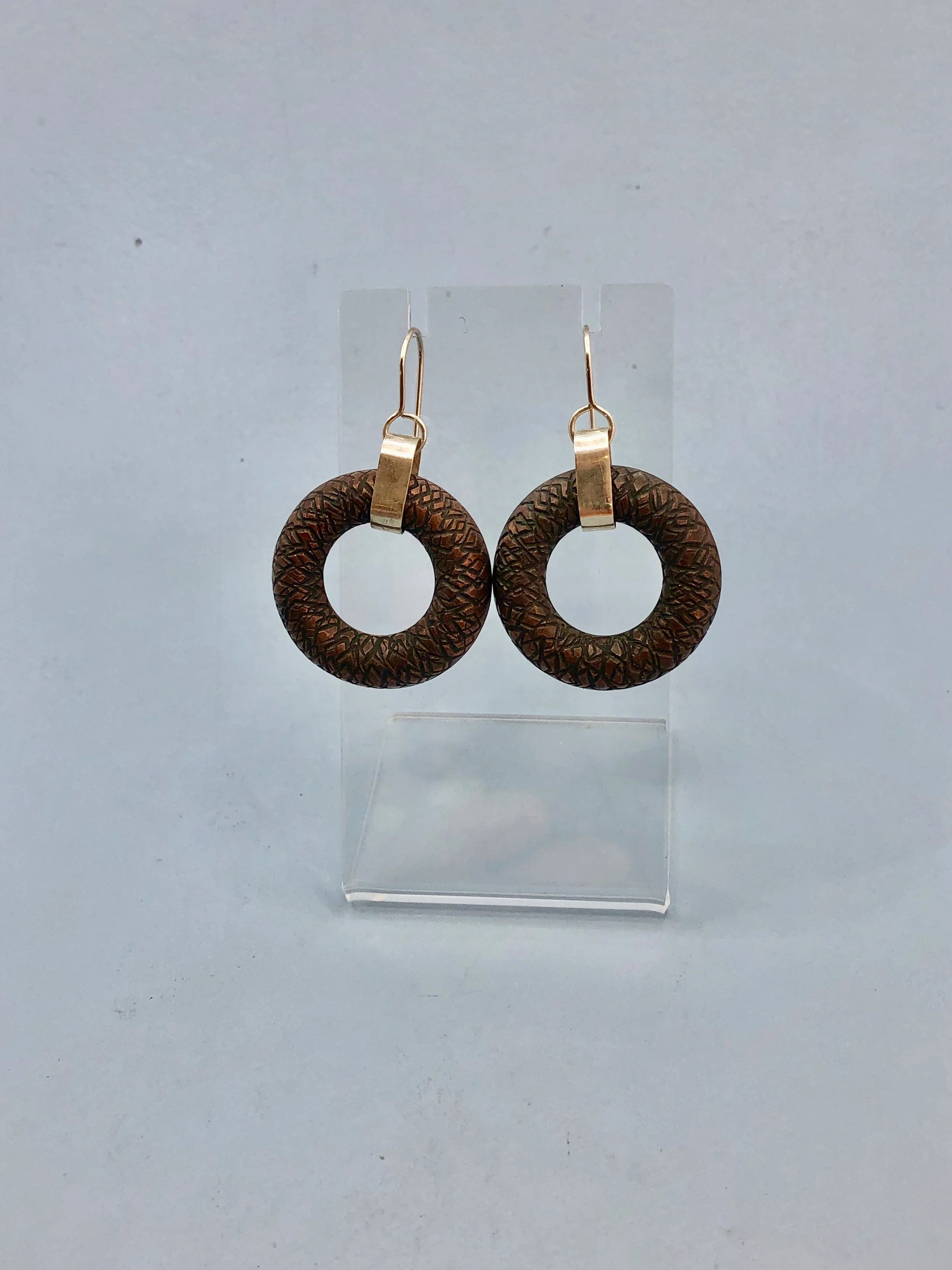Textured copper donut shaped earrings shown hanging