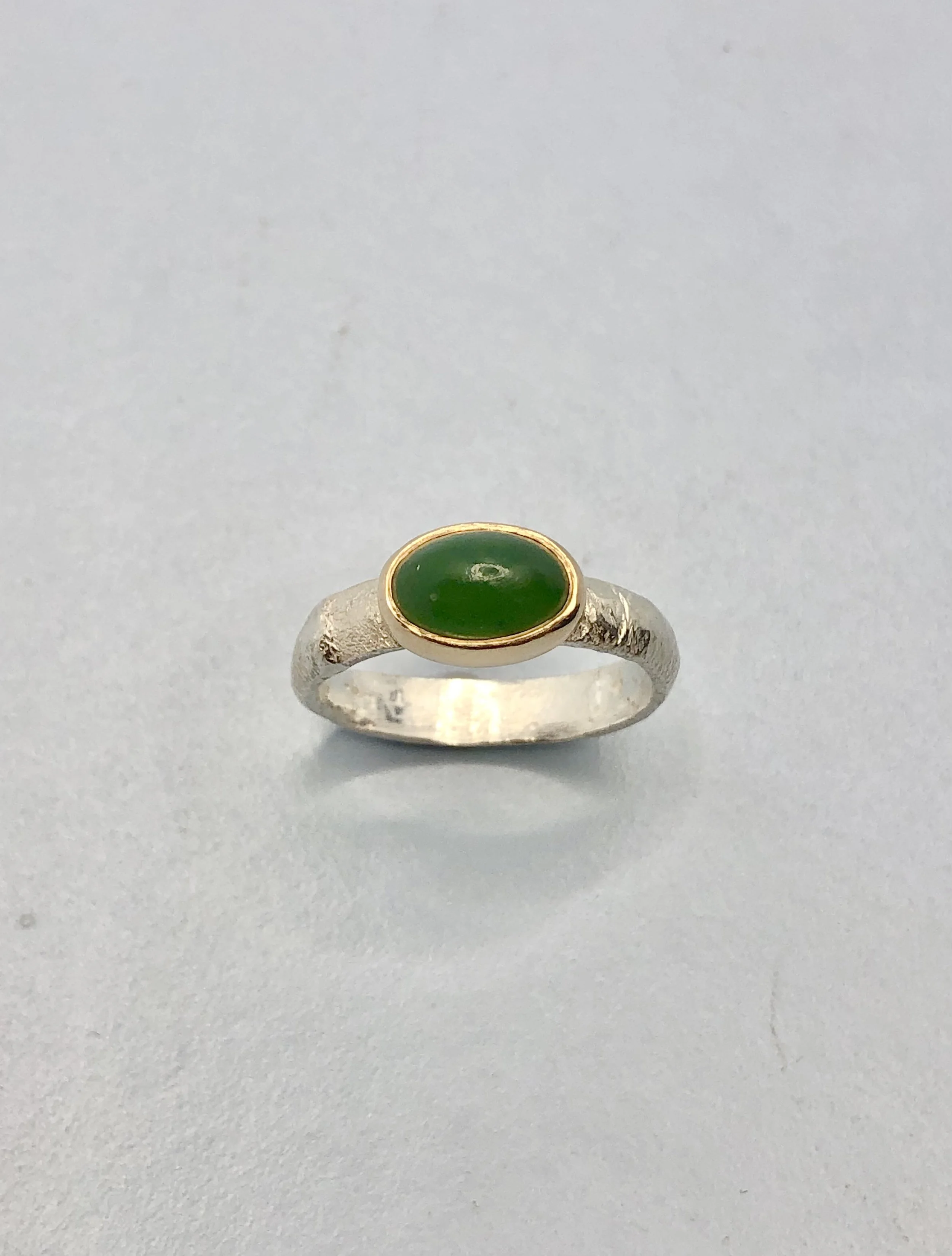 Hand carved oval pounamu ring set in 9k yellow gold and textured sterling silver. Rachel Lambert Jewellery