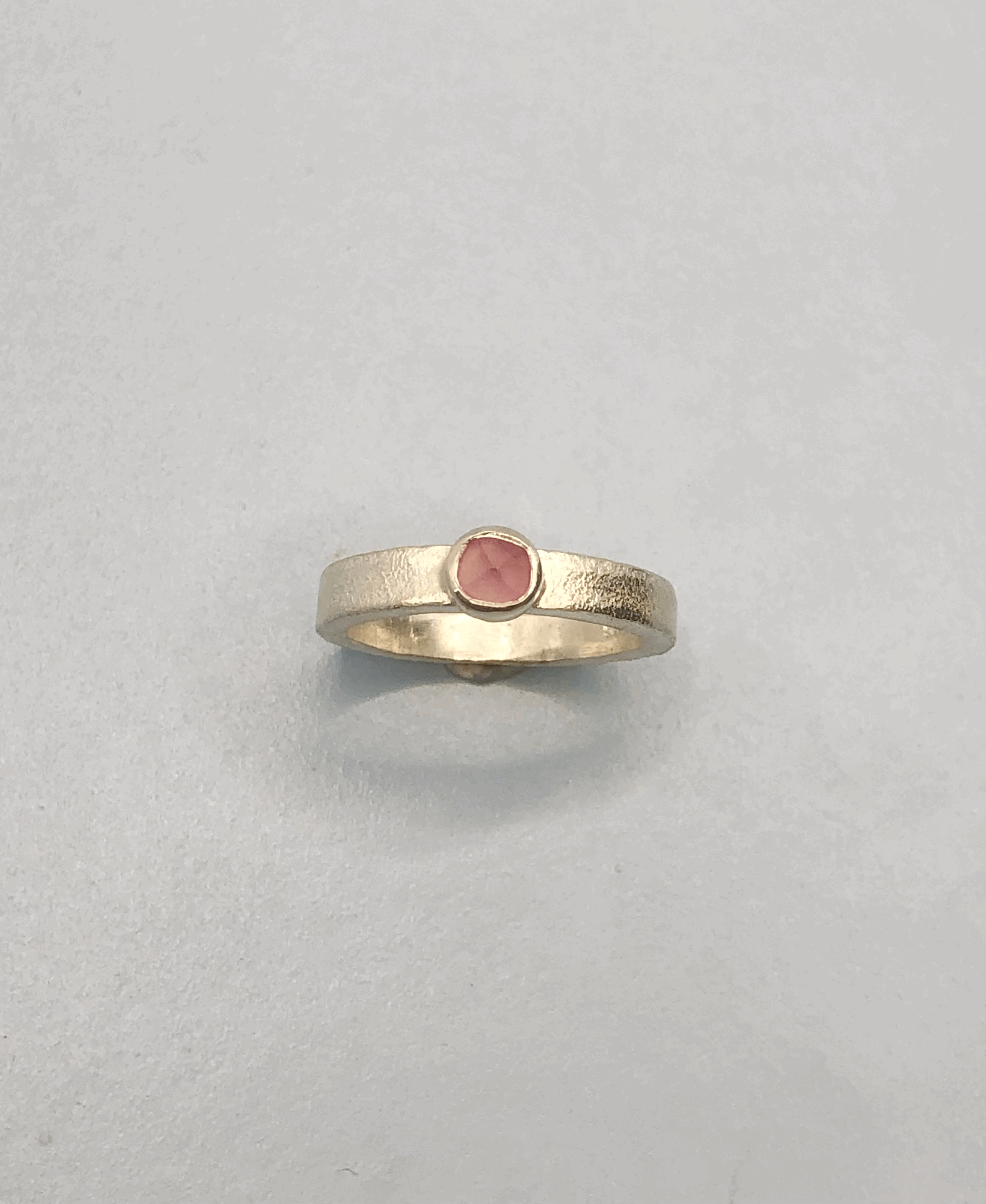 Rough cut pink tourmaline set in square sterling silver bezel on textured rectangular band ring. Rachel Lambert Jewellery