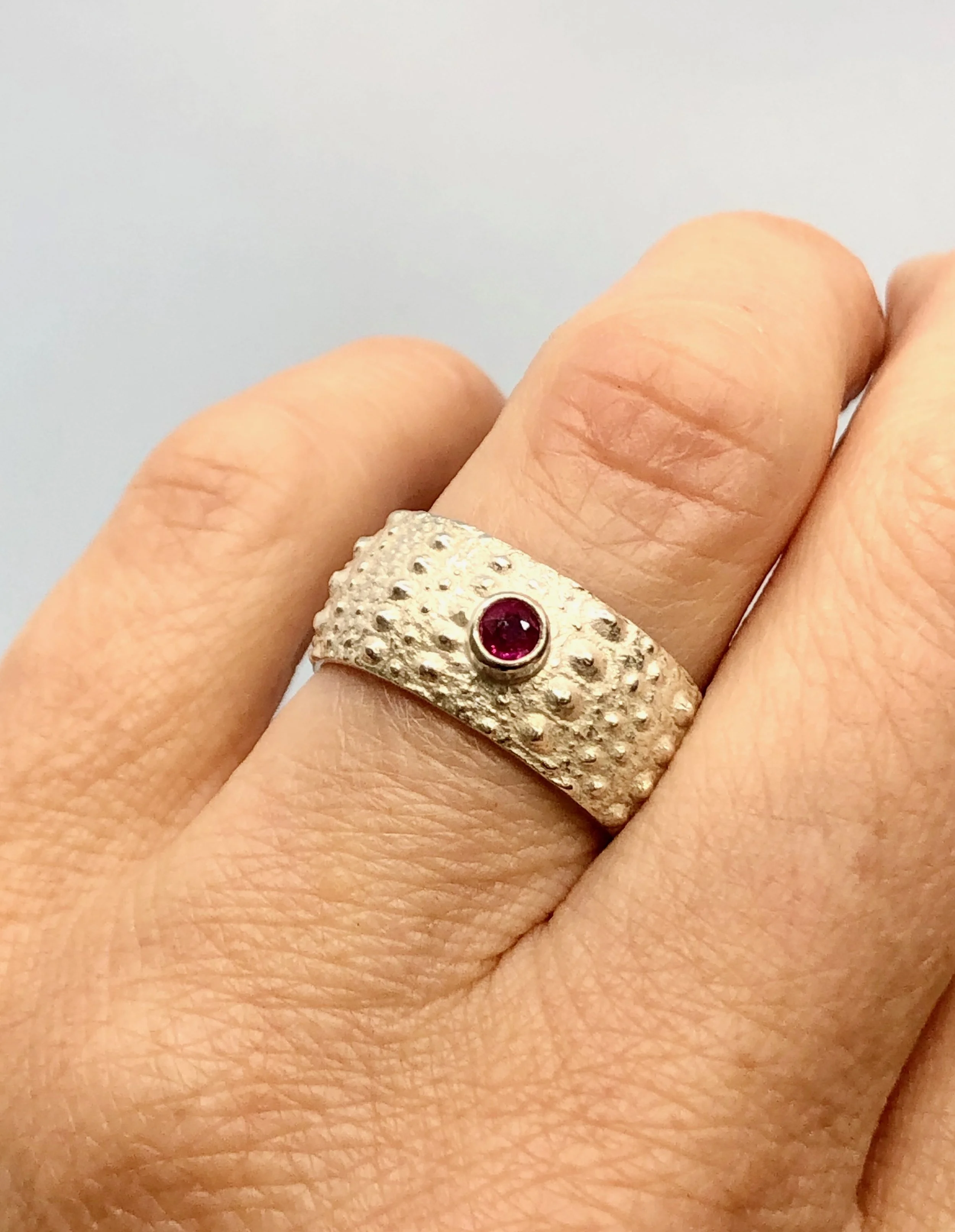 Ruby and sterling silver Kina textured ring shown worn on a finger to show fit