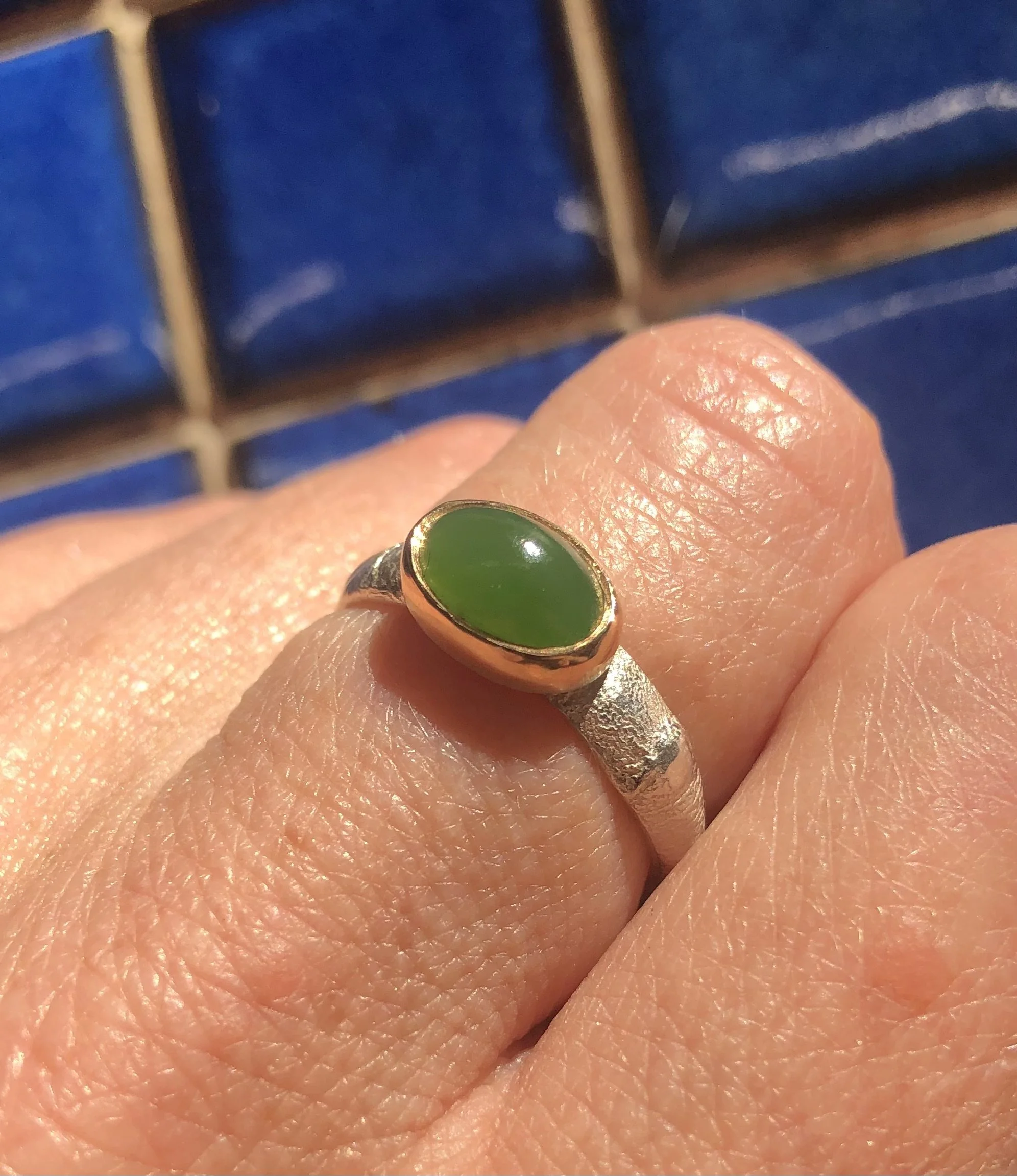 Pounamu and gold ring worn on hand, showing size and scale.
