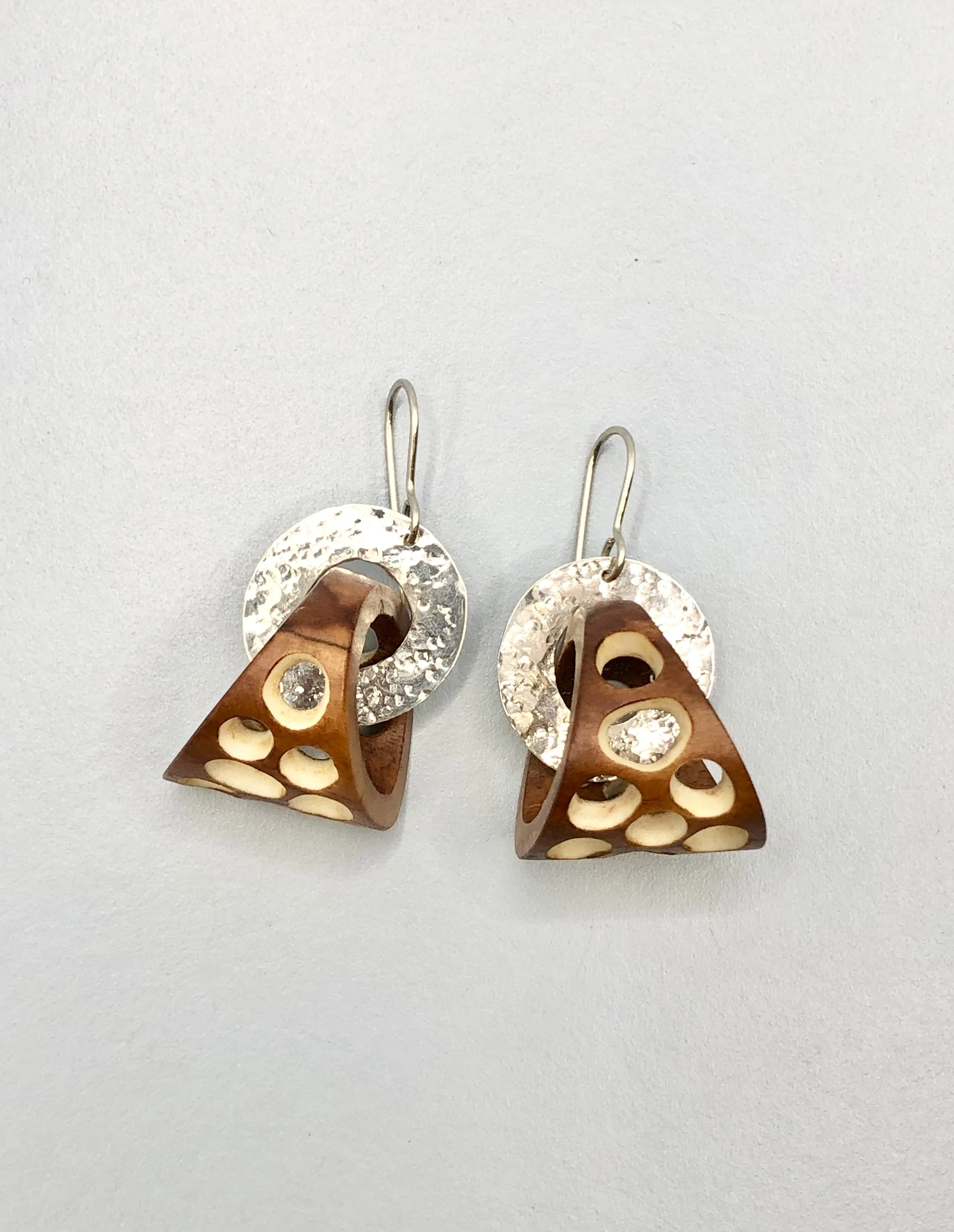 Pair of small antler basket hoop earrings laid flat showing organic natural tones and silver detail