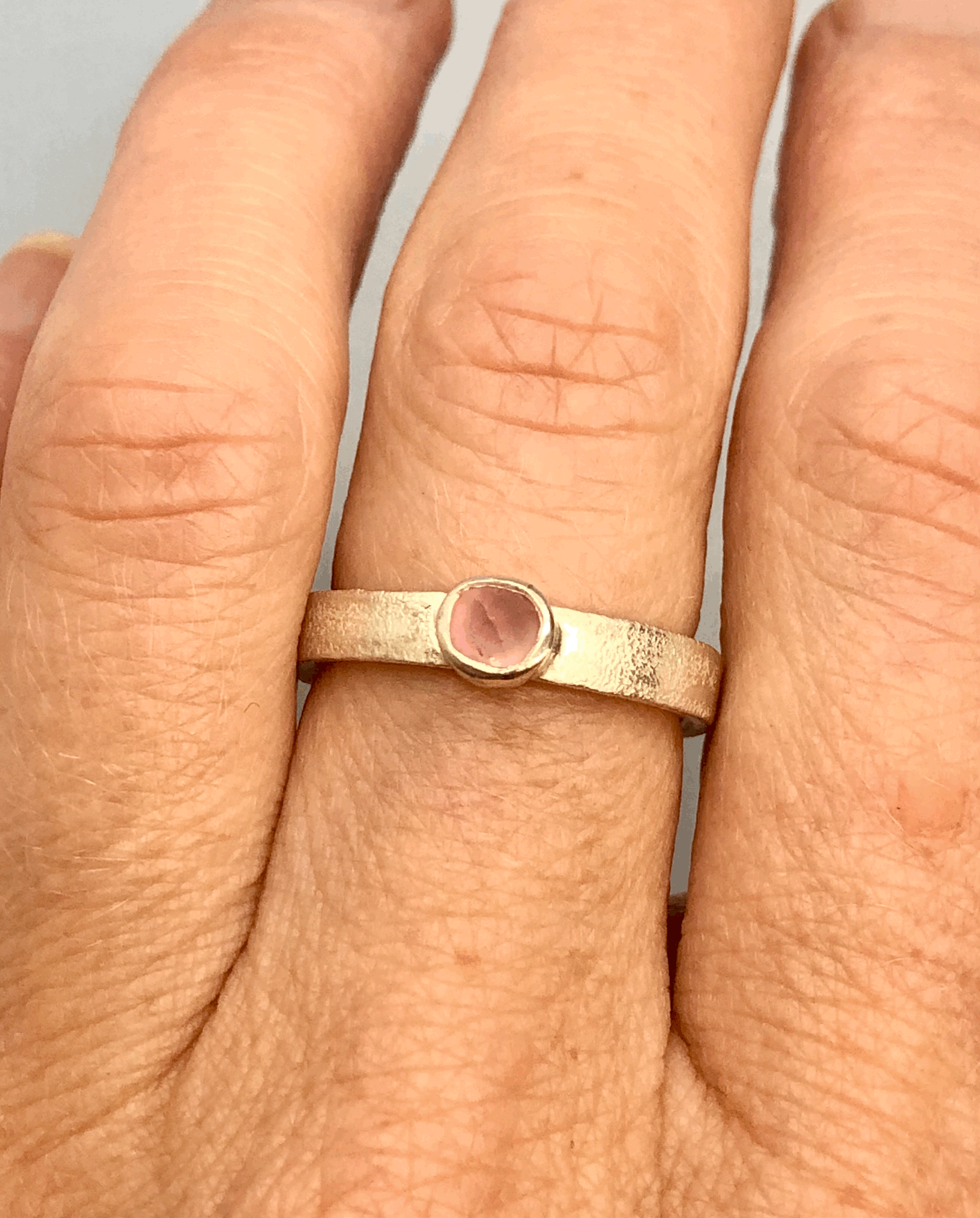 Pink tourmaline sterling silver stacker ring worn on finger showing size O½ fit and delicate 3.5mm band width
