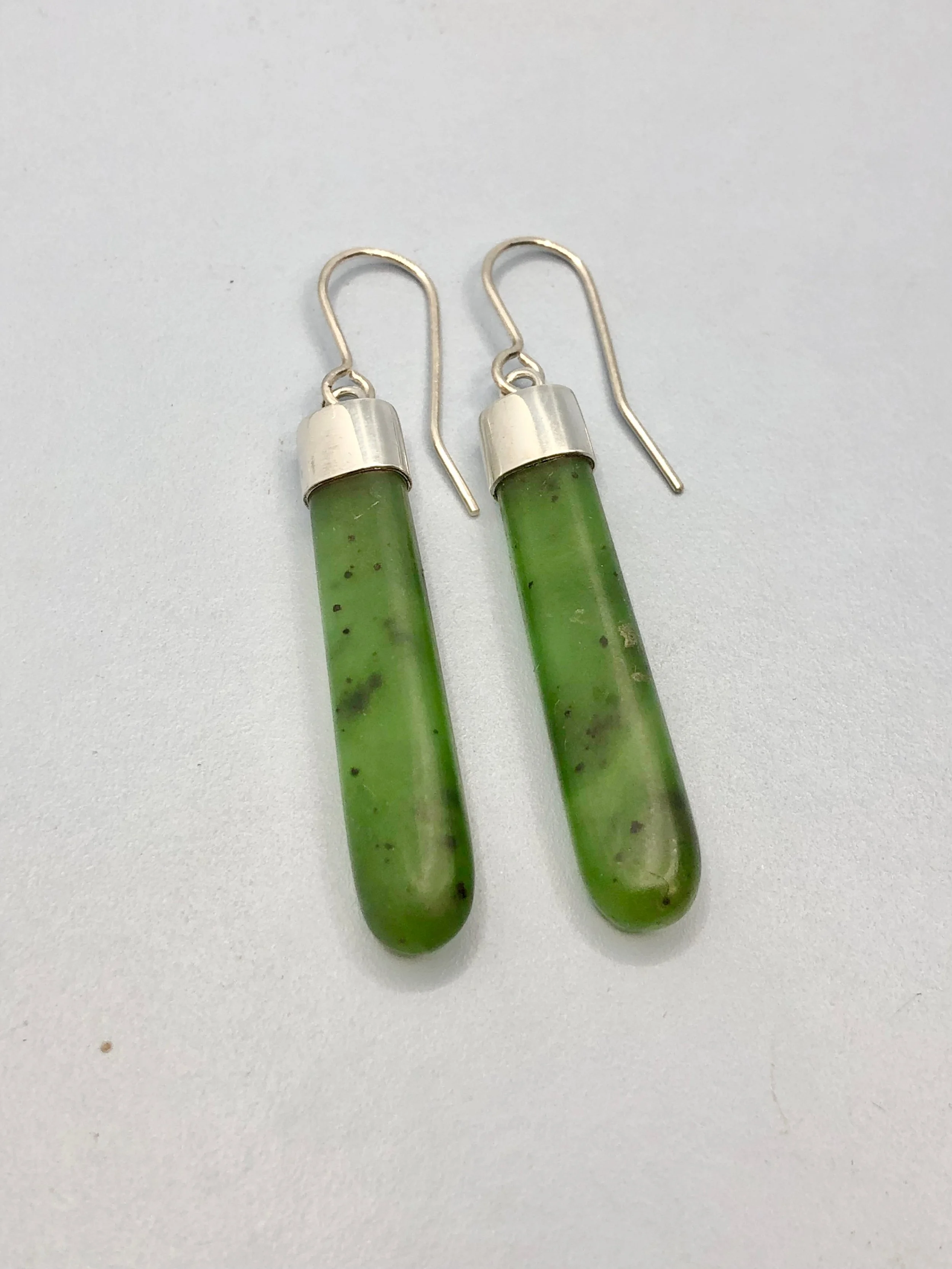 NZ greenstone earrings hand carved with handmade sterling silver cap attachments lying down