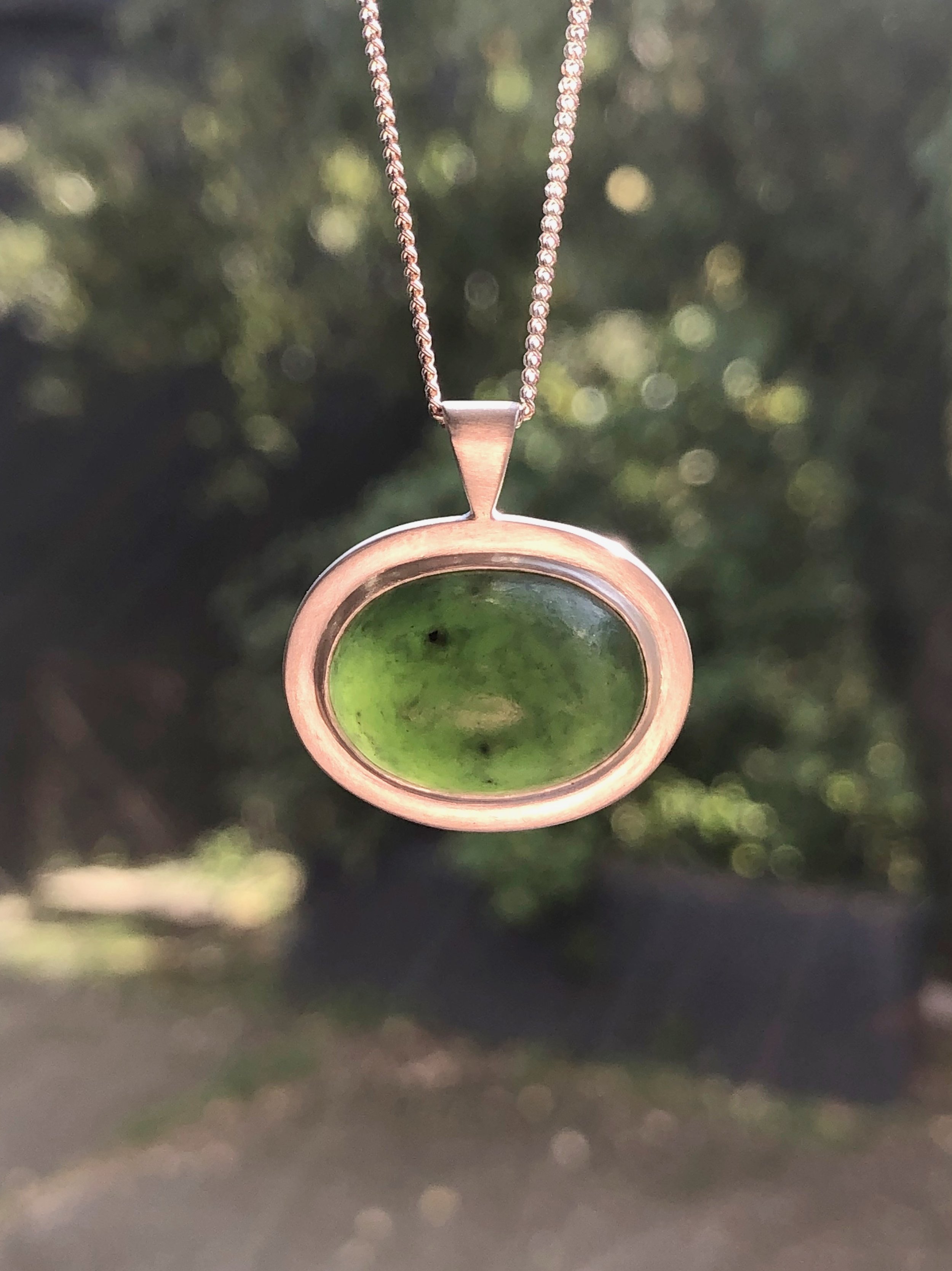 NZ Pounamu pendant hanging in the light to show translucency