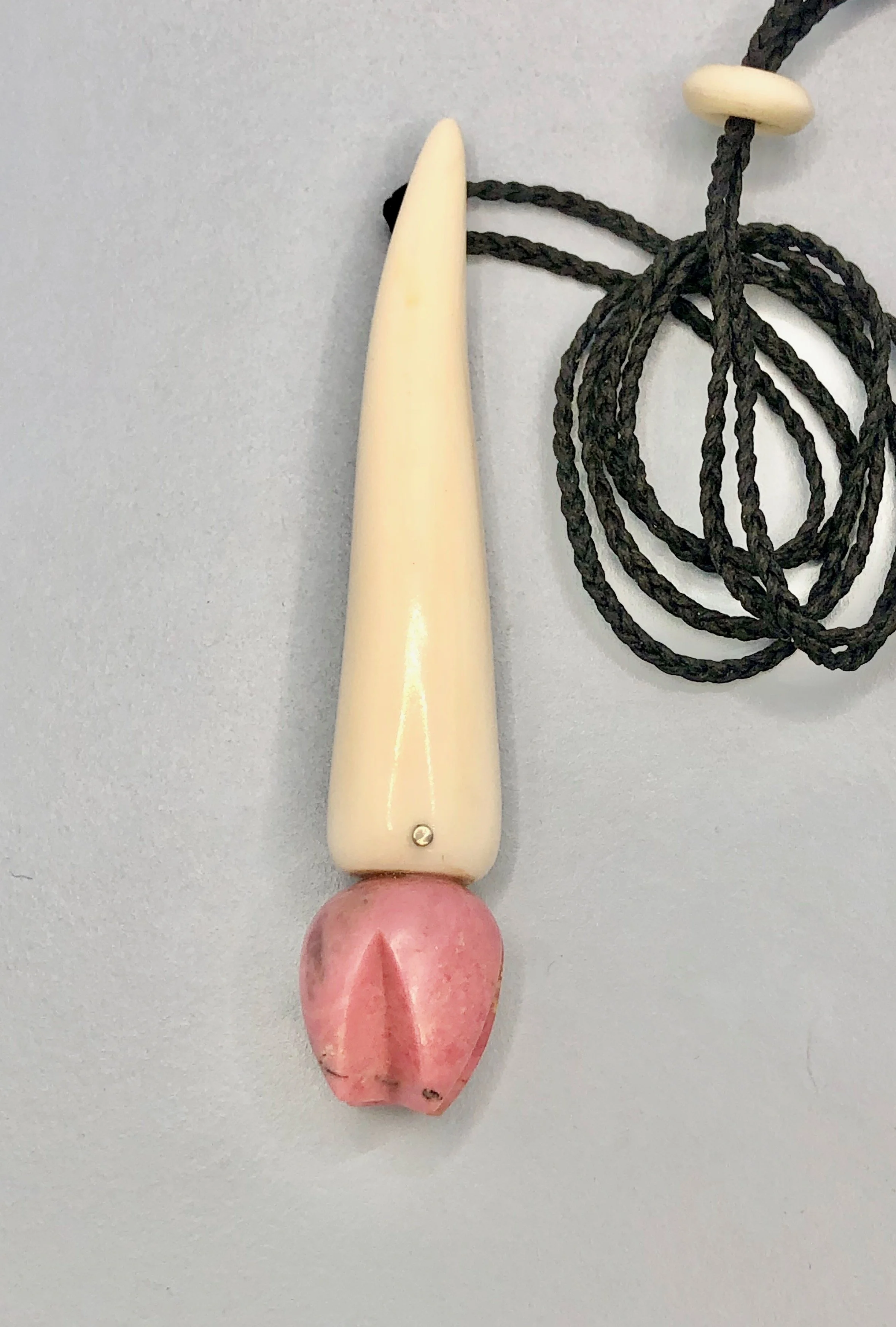 Front view of pink rhodonite and antler pendant showing adjustable wax plaited cord