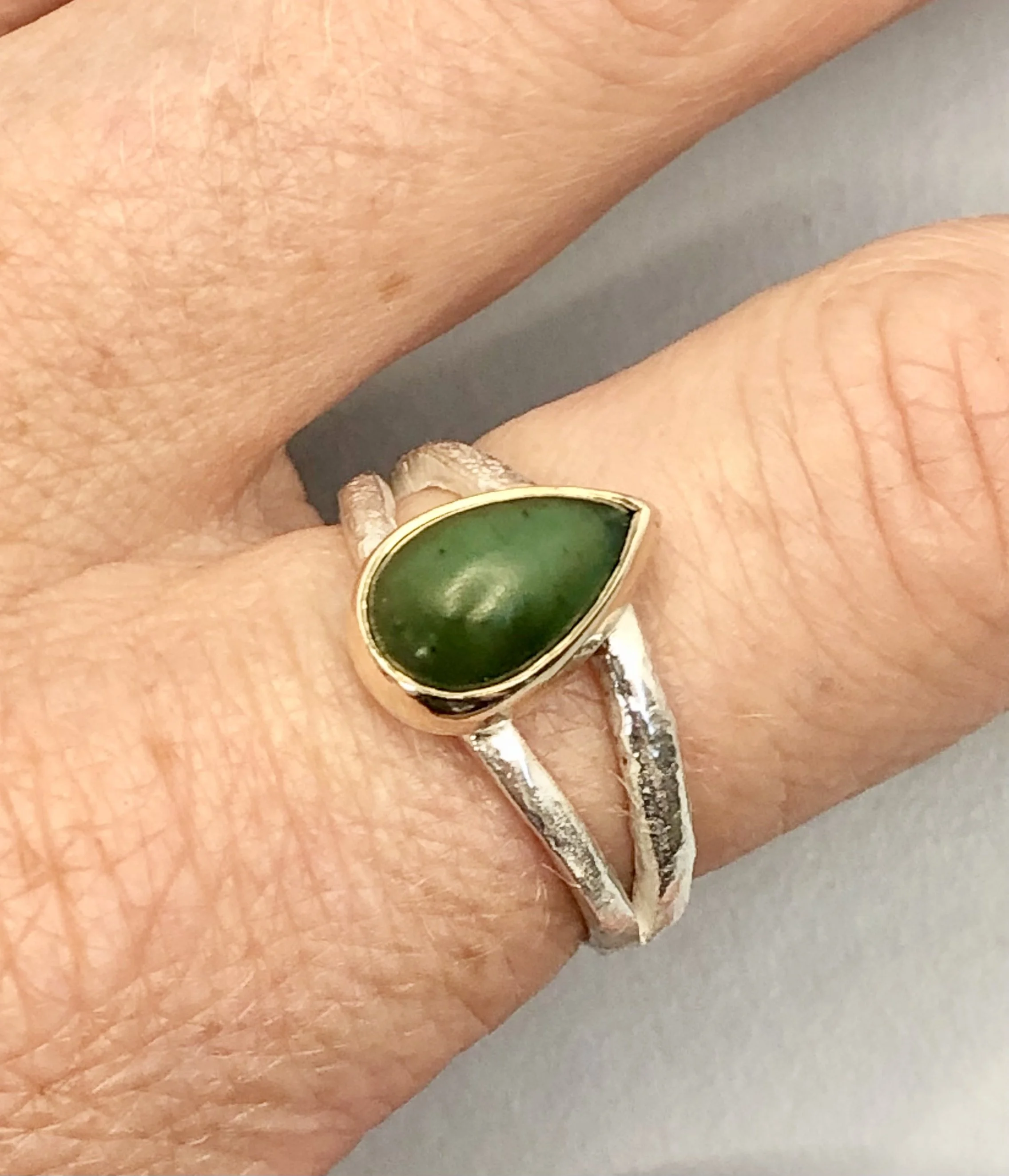 Pounamu teardrop ring worn on finger showing size R½ fit, handcrafted New Zealand jewellery