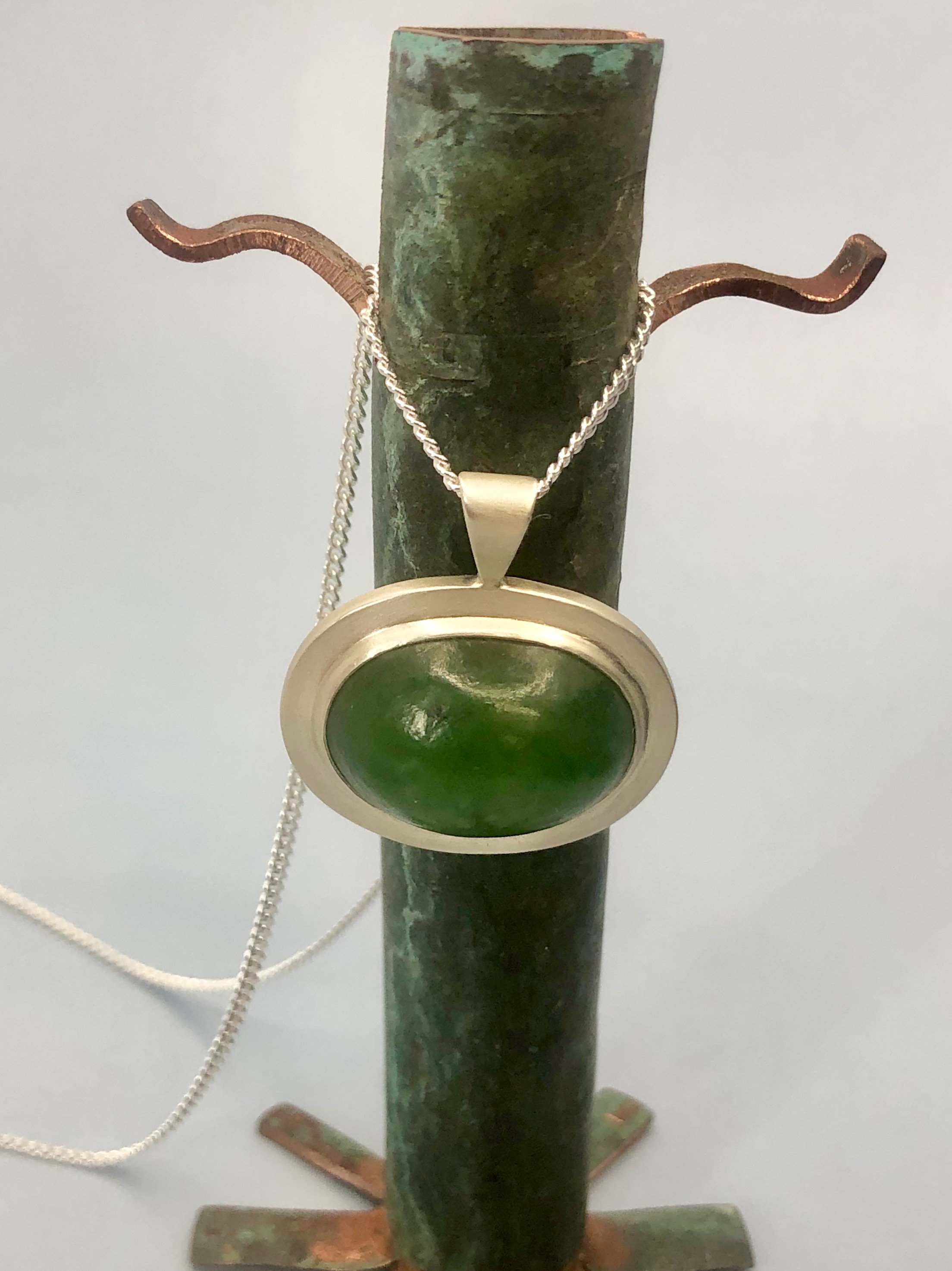 Pounamu dome pendant shown hanging from 925 curb chain.
